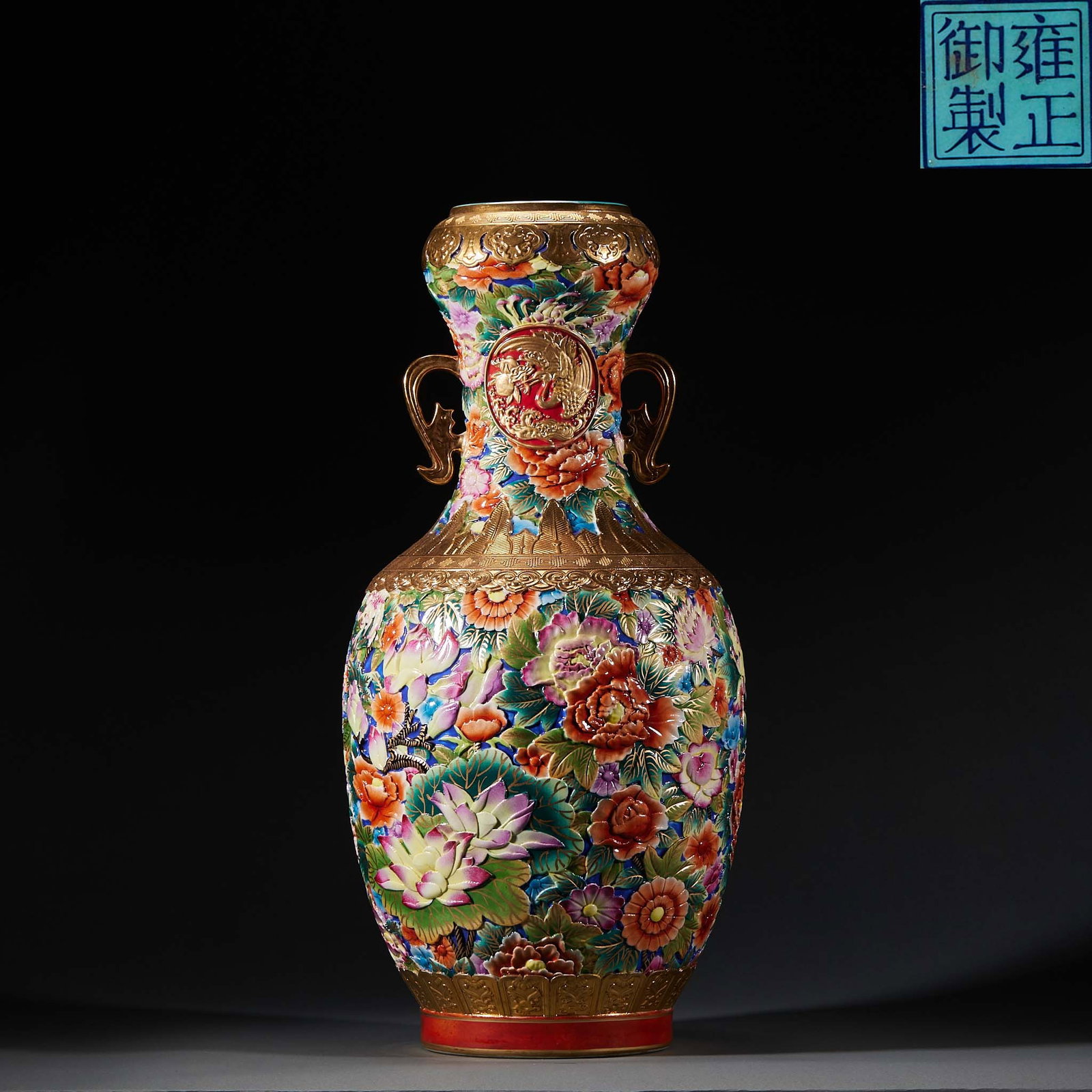 Yongzheng Famille-Rose 'Hundred Flowers' Garlic-Head Vase with Double Ears: The base bears the Yongzheng imperial mark. The body is covered in high relief with four-season flowers layered and full; the shoulder has gilt bat ears and the belly centre a round dragon-phoenix rel