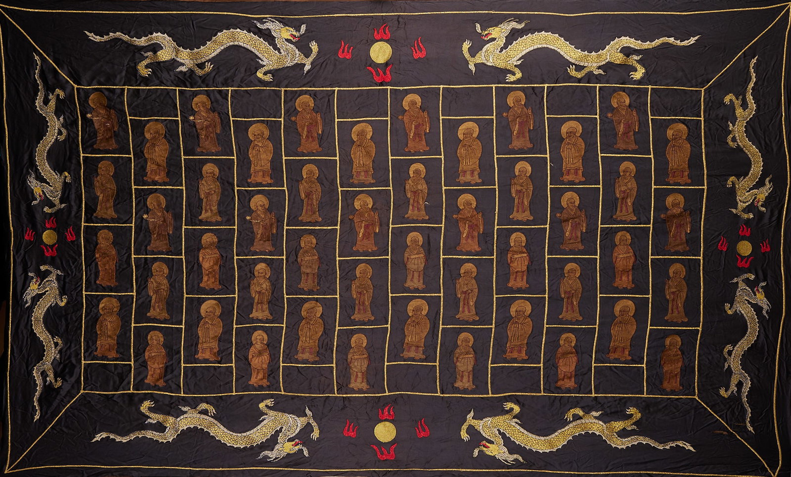 Embroidered Arhat Monk's Robe in Gold-Silver Thread: A black-ground satin monk's robe worked in couched-gold and seed-stitch. The interior is divided into compartments embroidered with forty-eight arhats, bordered with five-claw walking dragons, with
