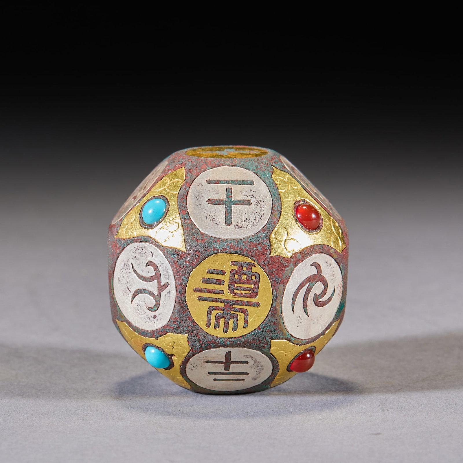 Inlaid-Gold-and-Silver Eighteen-Face Gem-Inlaid Dice: An eighteen-face bronze die inlaid with gold and silver, set with turquoise and red agate, each face inscribed. It was used in Han drinking and gambling games; the prototype comes from the tomb of Dou
