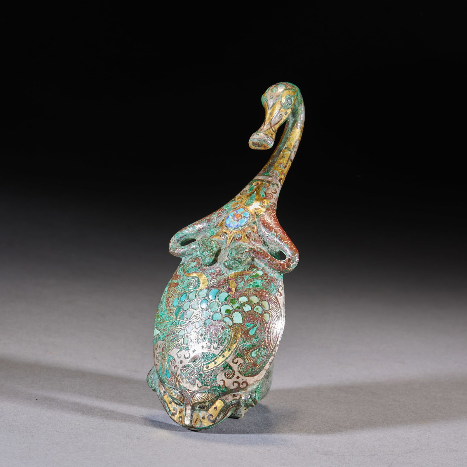 Inlaid-Gold-and-Silver Turquoise-Inset Phoenix Goose-Head Belt Hook: A Han-style bronze belt hook in phoenix-bird form, inlaid with gold and silver and set with turquoise, engraved with scale and cloud patterns. Belt hooks fasten the belt ?? a common dress fitting of W