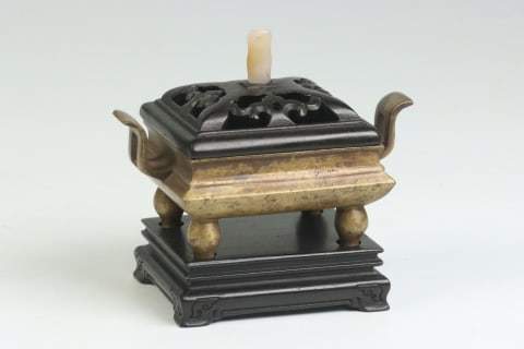 Four-Footed Twin Upright-Ear Bronze Censer, Jiajing Gengyin, Great Ming: A square bronze censer with court-hat ears and four breast-shaped feet, fitted with an openwork rosewood cover topped with a white-jade knob, plus a rosewood base. Imitating the Xuande burner ?? a sch