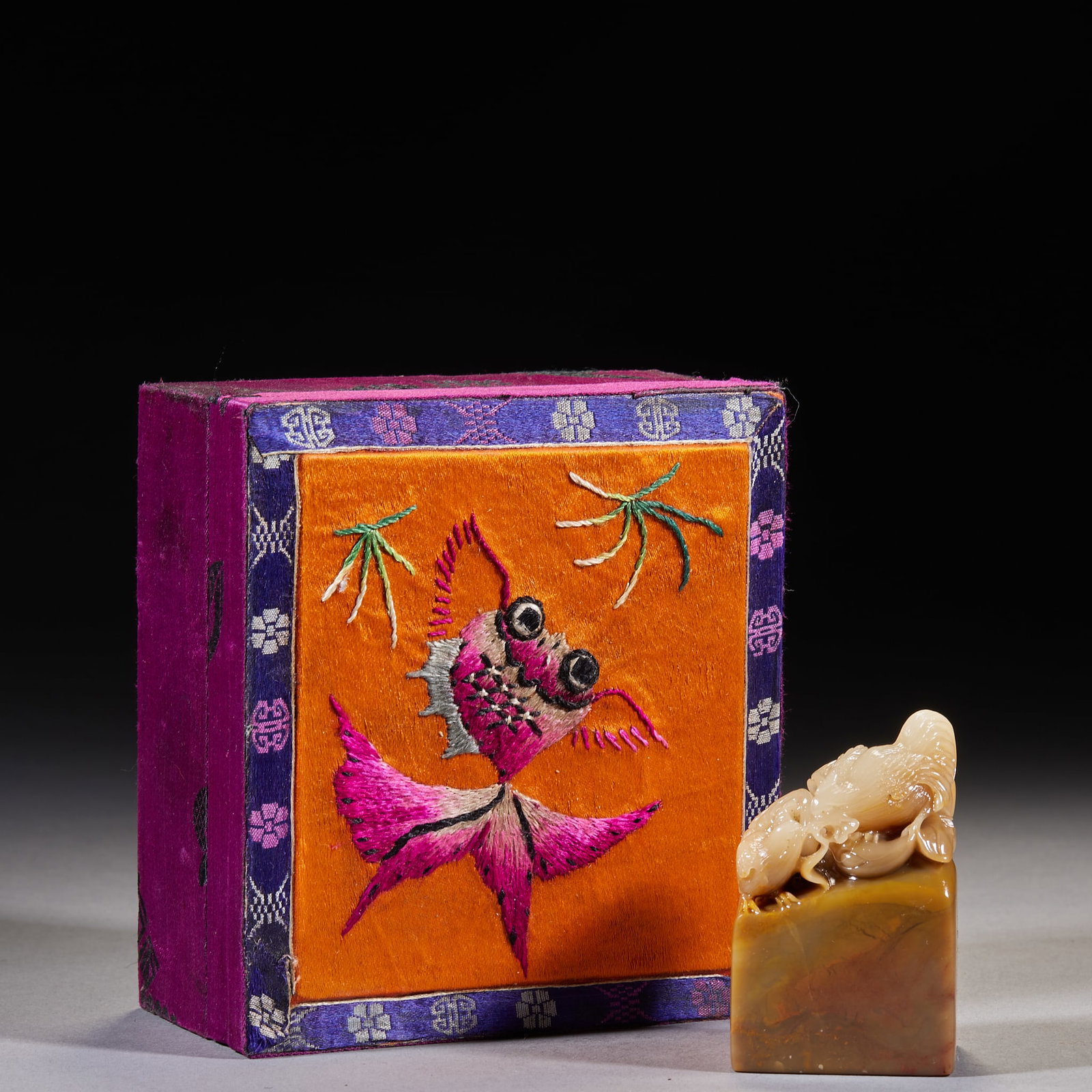 Shoushan 'Blue-Bird Holding Flower' Uninscribed Seal: A square Shoushan seal with a clever carving of a squirrel among melons and fruits on top, white-and-yellow stone. Supplied with a Qing brocade-embroidered seal box whose lid is embroidered with