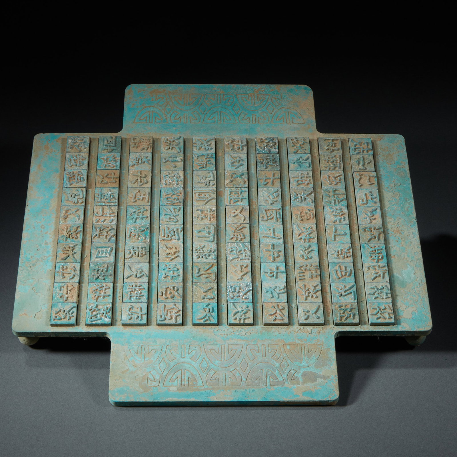 Western Xia Movable-Type Printing Plate: Cast bronze in a cross-shaped base carrying multiple rows of removable Han movable type; the surface is covered in blue-green patina and decorated with old patterns, replicating an ancient movable-typ