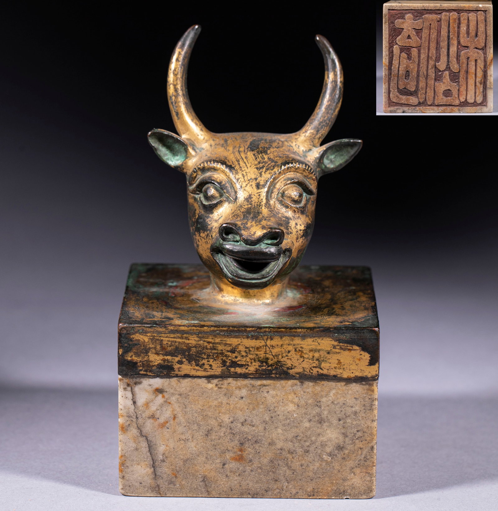 Ox-Head Large Seal: A square seal platform topped with a gilded ox head, horns upright and features realistic. The platform is old stone, the underside cut with seal-script characters ?? both display and sealing