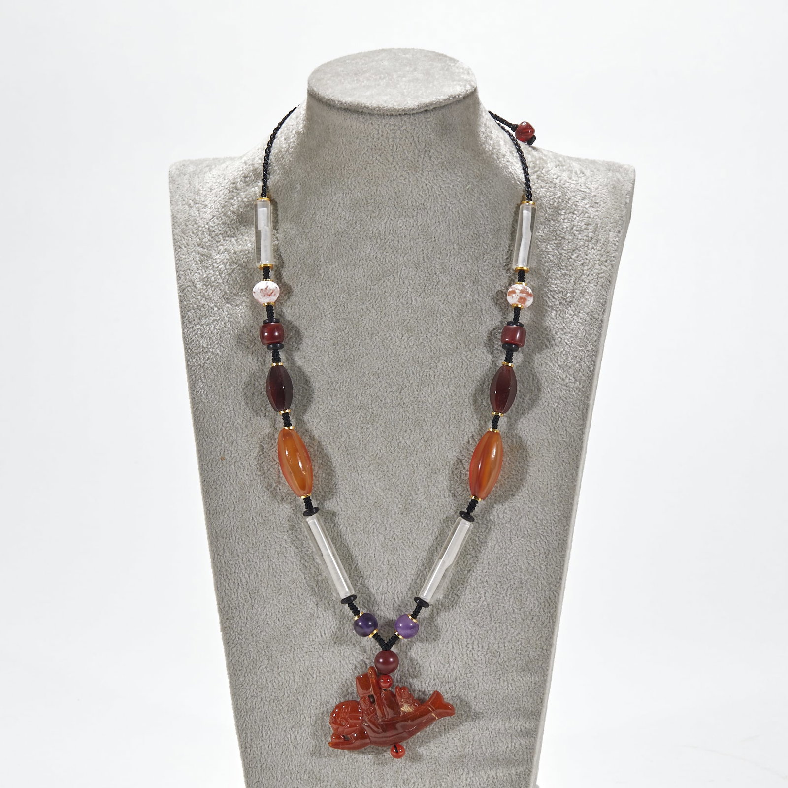 Amber 'Smooth Sailing' Pendant with Crystal and Agate Beads: A multi-treasure necklace strung of agate, crystal tube beads, amethyst and other gems, with a red-agate mythical-beast pendant as finial ?? an old-bead wearing collection. Amber L 5.5 cm, W 3.5 cm.