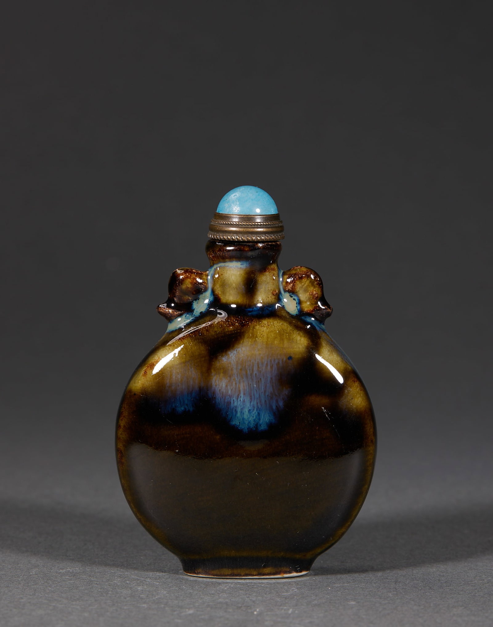Qing Transmutation-Glaze Snuff Bottle: A flat porcelain snuff bottle with beast-head ears on both sides, glazed overall in transmutation glaze ?? brown base suffused with blue transmutation blotches, lustrous and glossy. Fitted with a meta