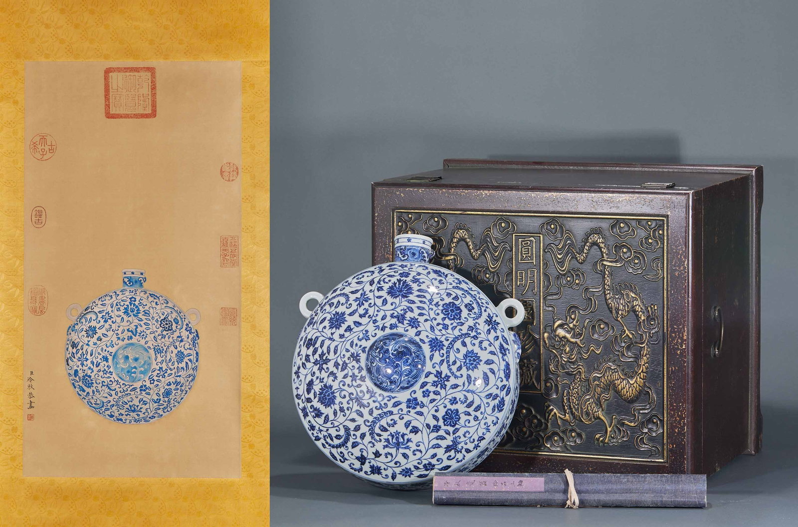 Ming Underglaze-Blue Scrolling-Lotus Reclining Flask: An underglaze-blue moon-flask with beast-head loop ears at the sides, painted throughout with scrolling floral, the centre front with a medallion dragon. With a dragon-carved scripture wood case and a