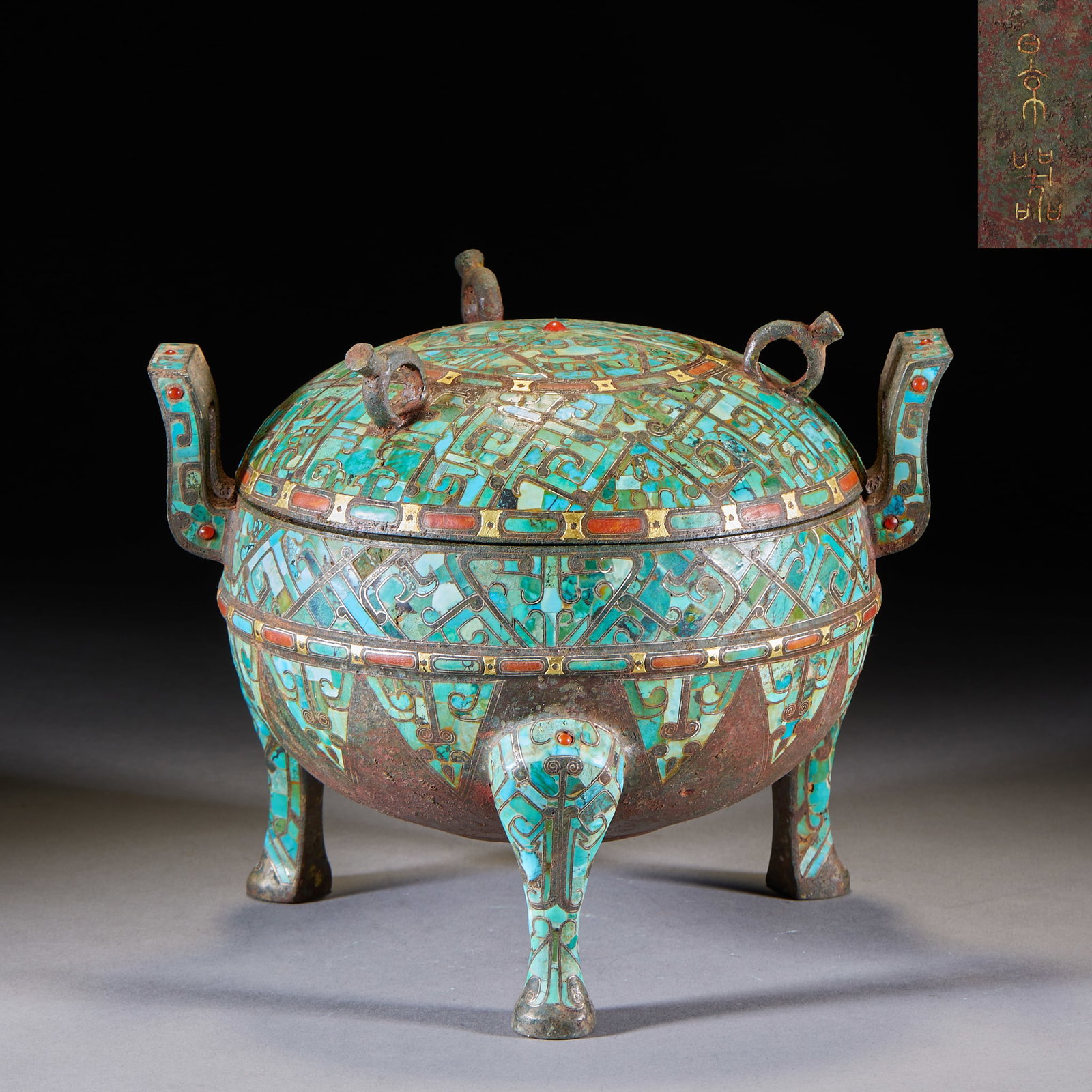 Inlaid-Gold-and-Silver Turquoise-Inset Tripod Upright-Ear Covered Censer: A bronze ding with cover, two outward-turned ears and three beast feet. Body and cover are largely inlaid with turquoise with red-gem accents, in complex geometric patterns, bearing an inscription ??
