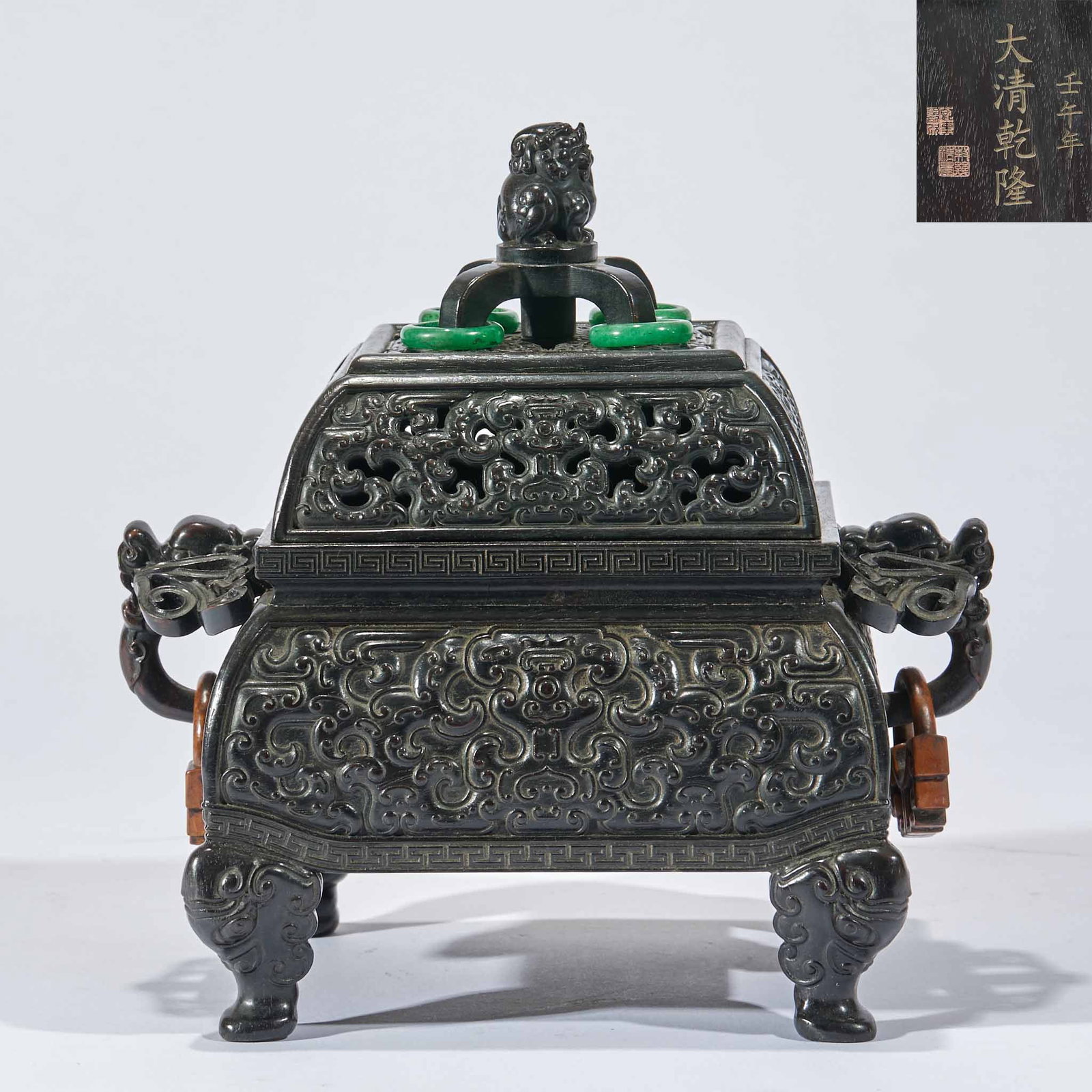 Qianlong Sandalwood Dragon-Eared Incense Burner: A spinach-green jade square censer whose cover is largely pierced with floral scrolls, topped with an auspicious-beast knop; the rim is set with jadeite rings. The body is carved all over with