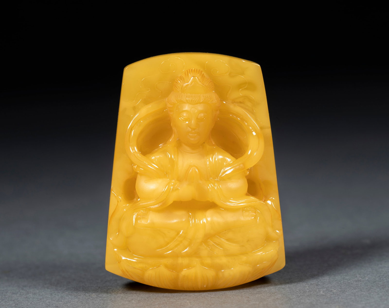 Amber Guanyin Plaque: An amber carving of a standing Guanyin holding a pure-vase, kindly face and flowing robes. The amber is orange-yellow, warm and translucent, finely carved. A hole at the top allows stringing ?? an