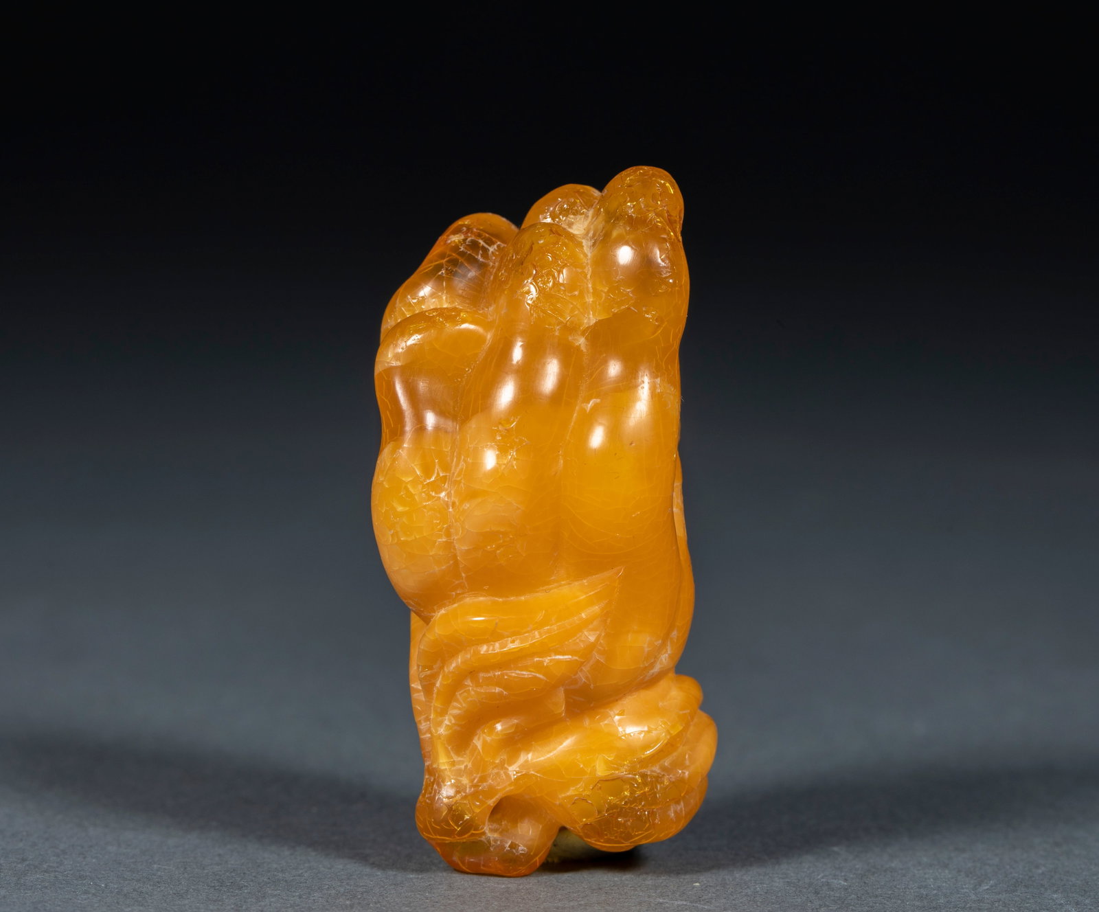 Amber Buddha's-Hand (Foshou): An amber round carving of a Buddha's-hand citron, full fruit with distinct fingers naturally spread. The amber is warm and translucent, finely carved. The Buddha's-hand symbolises fortune and