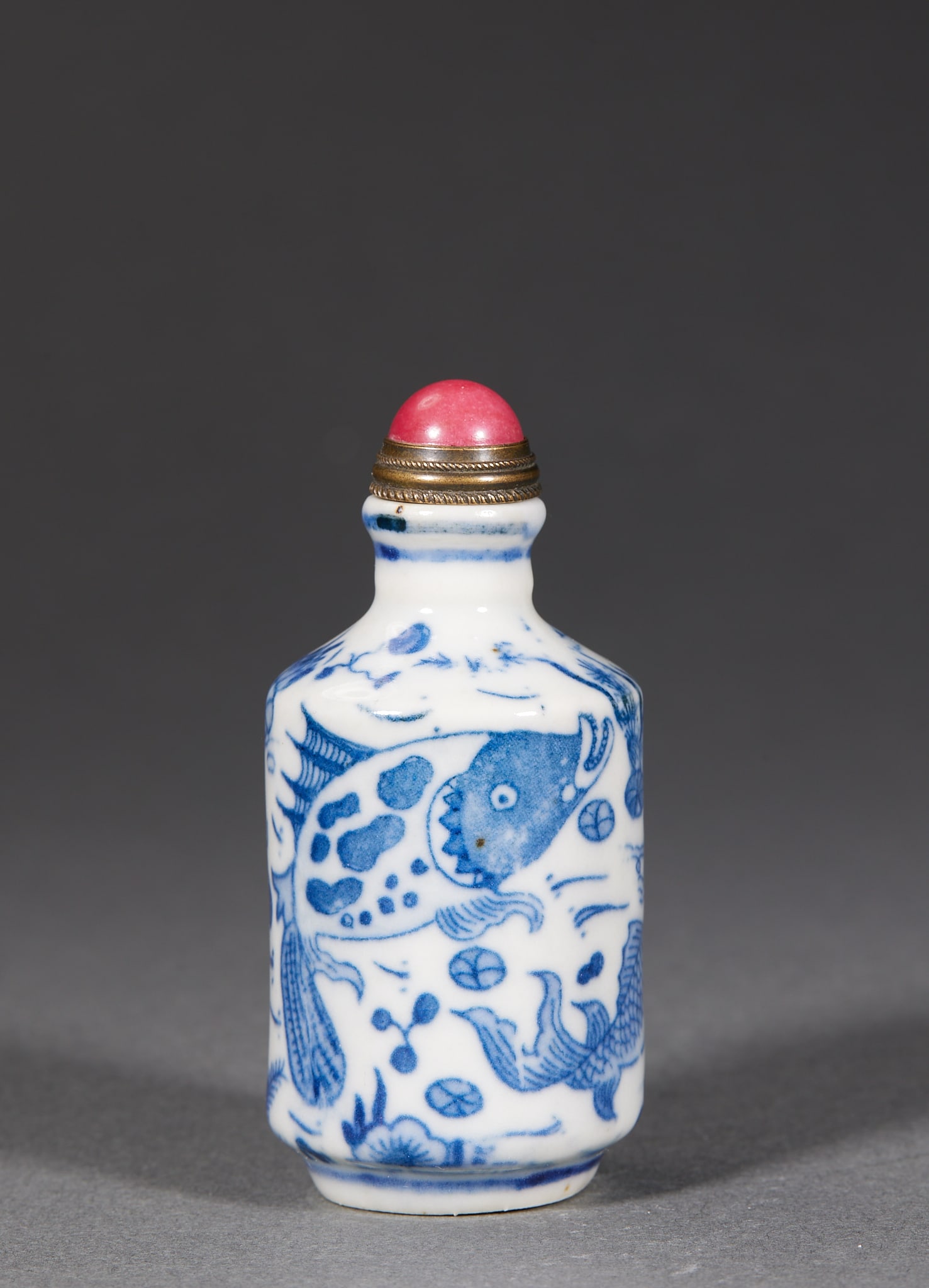 Qing Underglaze-Blue Fish-Play Snuff Bottle: A Qing underglaze-blue snuff bottle painted with fish at play among waterweeds, several swimming fish darting through the plants. The blue is bright, the glaze lustrous, the form small ?? a palm-piece