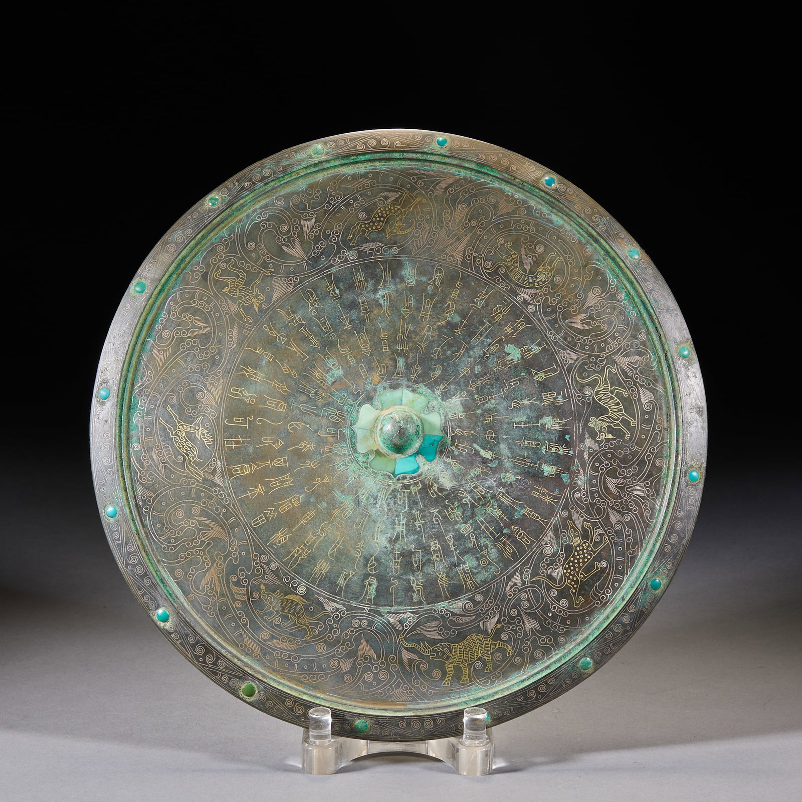 Inlaid-Gold-and-Silver Hundred-Beasts Bronze Mirror: A bronze mirror whose back is decorated in inlaid gold and silver with a hundred beasts running and leaping, the designs bright. Round with a small knob; the inlay is exquisite ?? a fine archaic