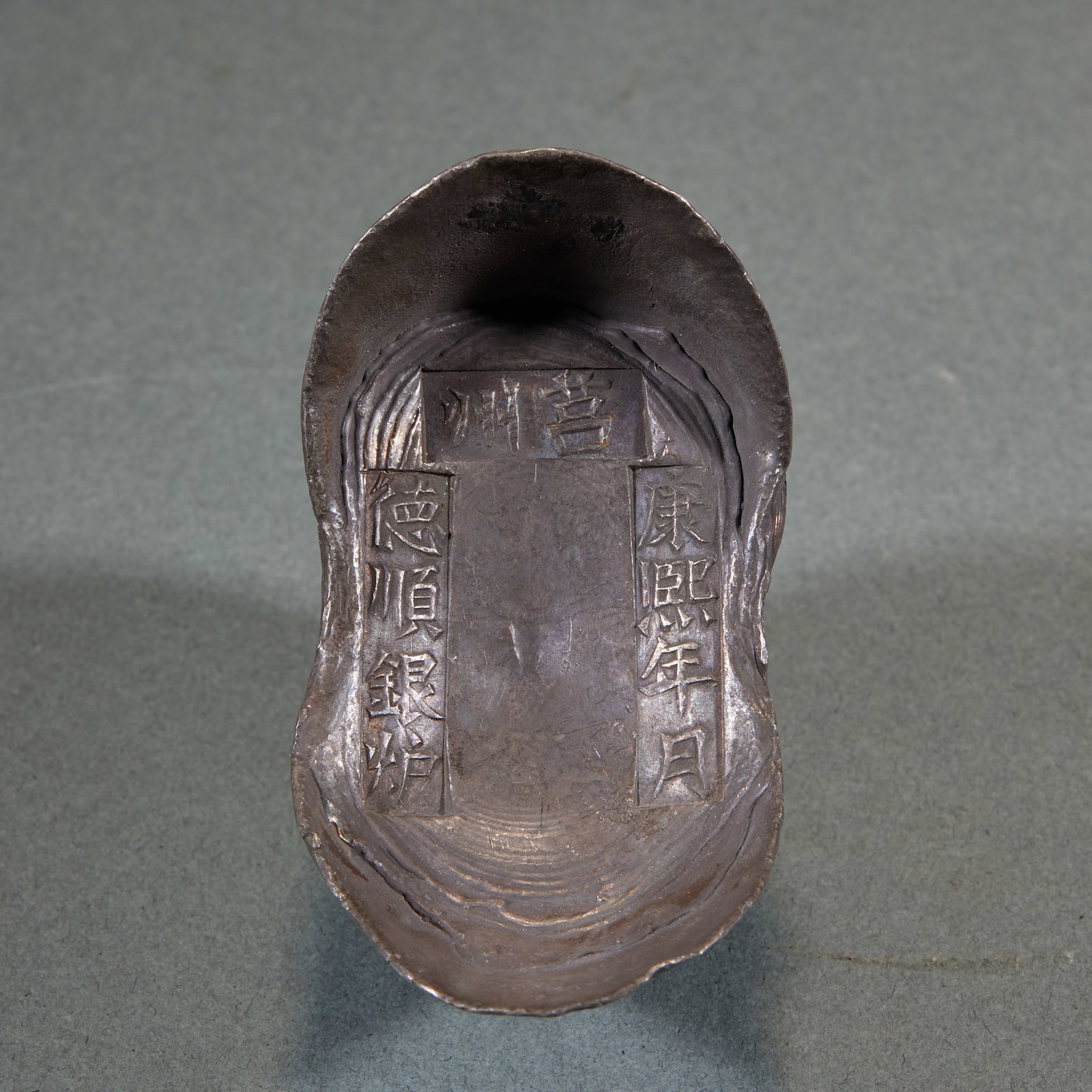 Qing Juzhou Deshun Silver Foundry Sycee, Kangxi Reign: A Qing Juzhou Deshun silver foundry sycee, regular in form, the face engraved with 'Juzhou', 'Kangxi reign' and 'Deshun' inscriptions recording the foundry, date and merchant. The silver is warm ?? a