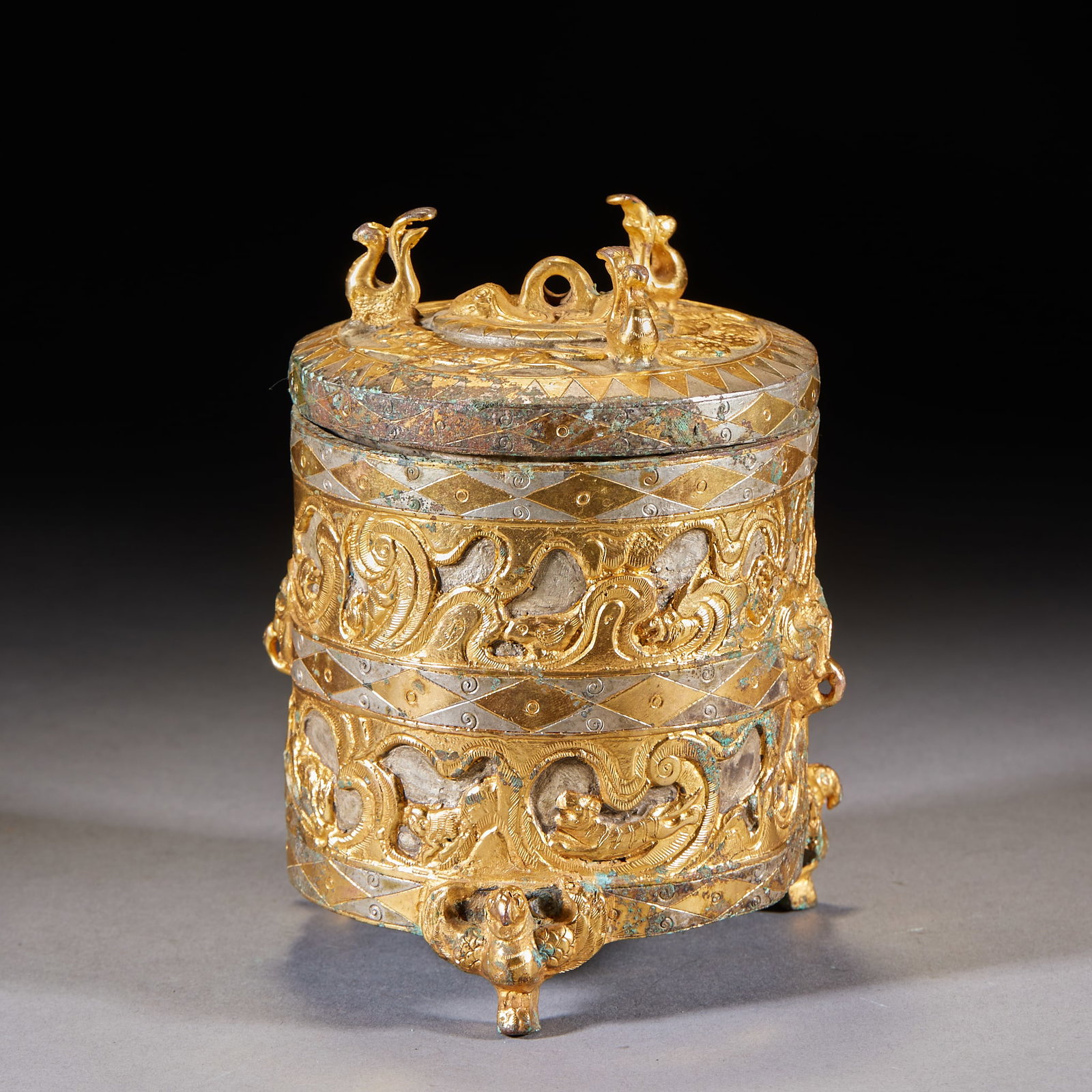 Inlaid-Gold-and-Silver Three-Beast-Foot Running-Beast Covered Jar: A covered jar inlaid with gold and silver in running-beast patterns, beasts running and leaping, the designs bright; with cover on three beast feet ?? a Han-style inlaid gold-and-silver bronze. H 14