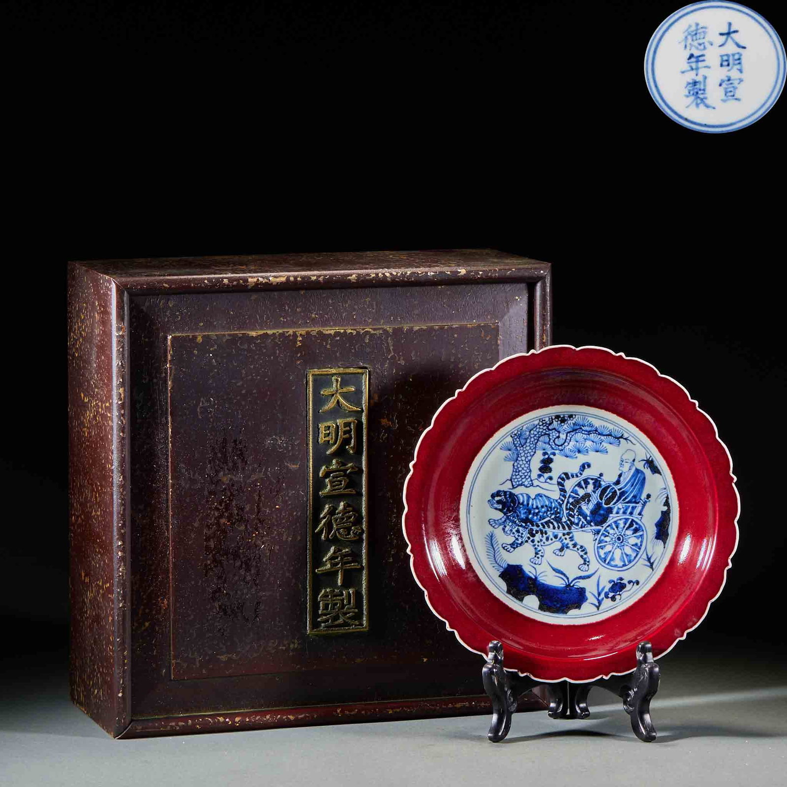Xuande-Marked Red-Glaze Underglaze-Blue 'Guiguzi Descending the Mountain' Flower-Rim Dish: A flower-rimmed dish painted in underglaze blue with Guiguzi descending the mountain: the figure rides an ox with attendants crowding ?? a lively scene; the base bears the mark 'Made in the Xuande
