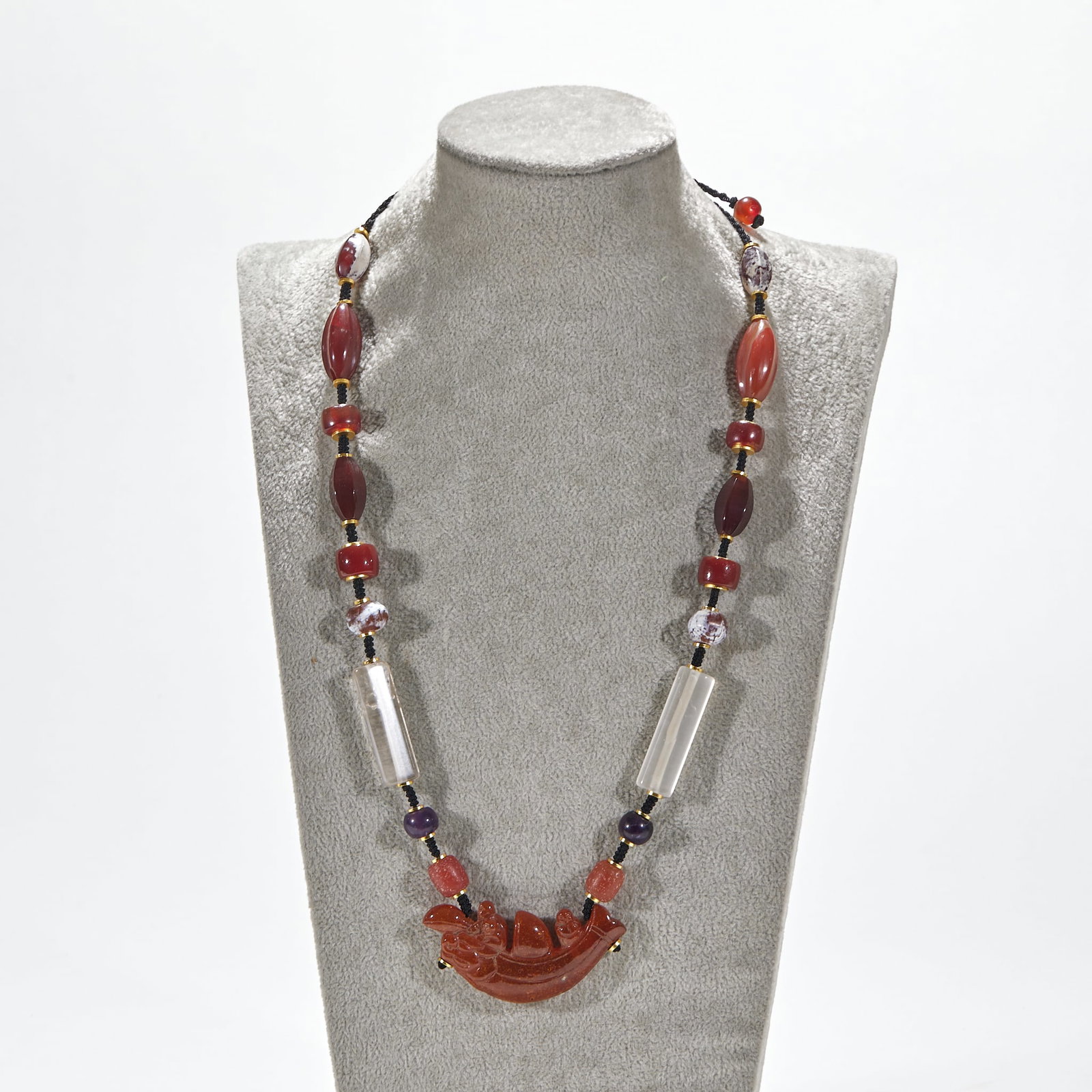 Amber 'Smooth Sailing' Pendant with Agate and Crystal Beads: An amber pendant carved as 'smooth sailing', combined with agate beads and crystal, strung as a pendant. The amber is warm, the crystal clear ?? symbolising smooth sailing. Amber L 6 cm, W 3 cm.
