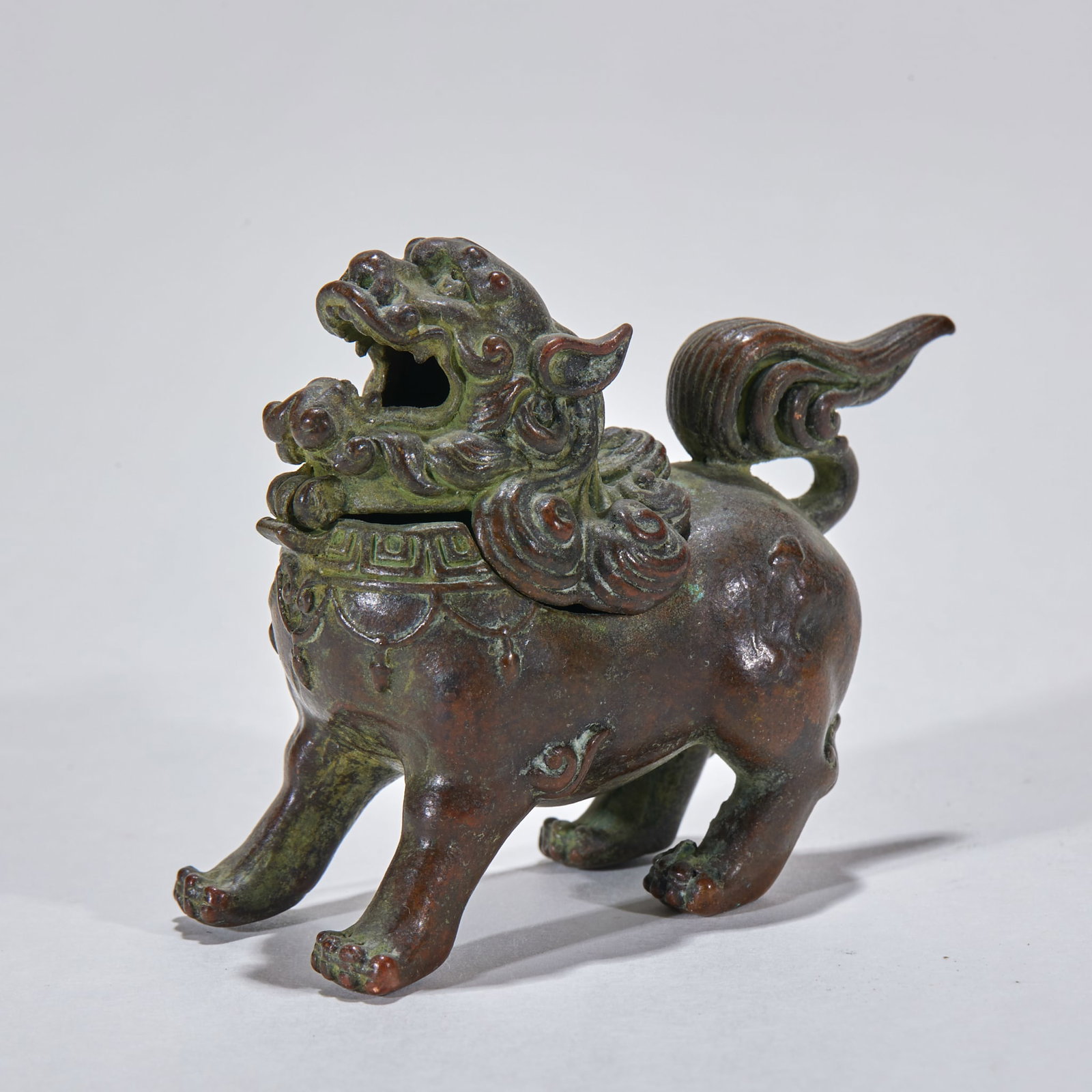 Copper Lion-Knop Incense Burner: A copper incense burner topped with a round-carved lion knop, the lion squatting, fierce. The body has a rounded belly on feet, warm copper with deep patina ?? an incense and display vessel. H 5.5