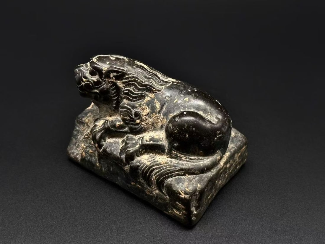 Desk Reclining Lion: A desk reclining-lion ornament of stone or jade, body reclining, serene, simply carved. A scholar's desk paperweight and display, symbolising guarding the home and warding off evil. H 8 cm, L 11 cm,