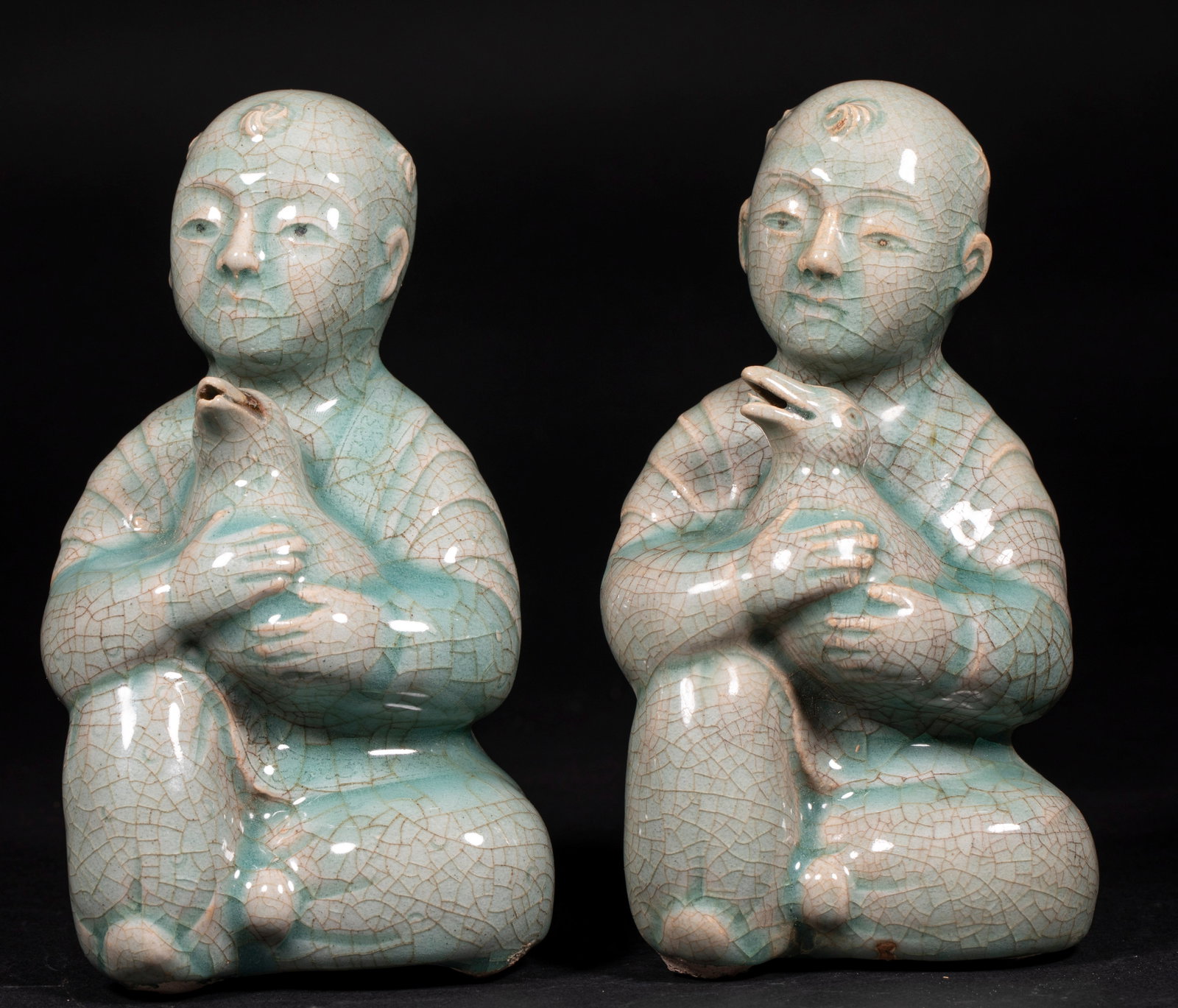 Pair of Goryeo Celadon Boy-Holding-Goose Water Droppers: A pair of Goryeo celadon water droppers modelled as a boy holding a goose, hollow to hold water. The celadon is green with ice-crackle, lively form, preserved as a pair. H 16 cm, L 9 cm, W 8.5 cm.