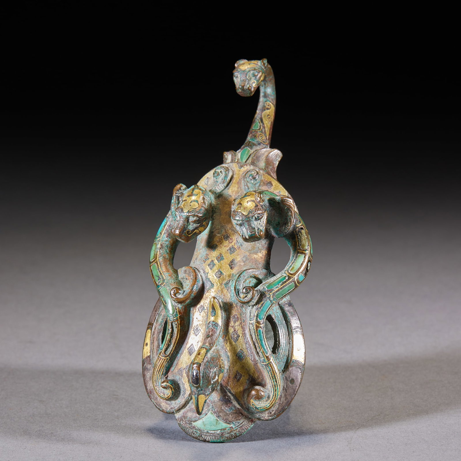 Inlaid-Gold-and-Silver Chi-Tiger Divine-Bird Belt Hook: An inlaid gold-and-silver belt hook in an arc form, the hook head with a divine bird, the body inlaid with gold and silver in chi-tiger patterns. Bright gold-silver decoration ?? a fine Han belt