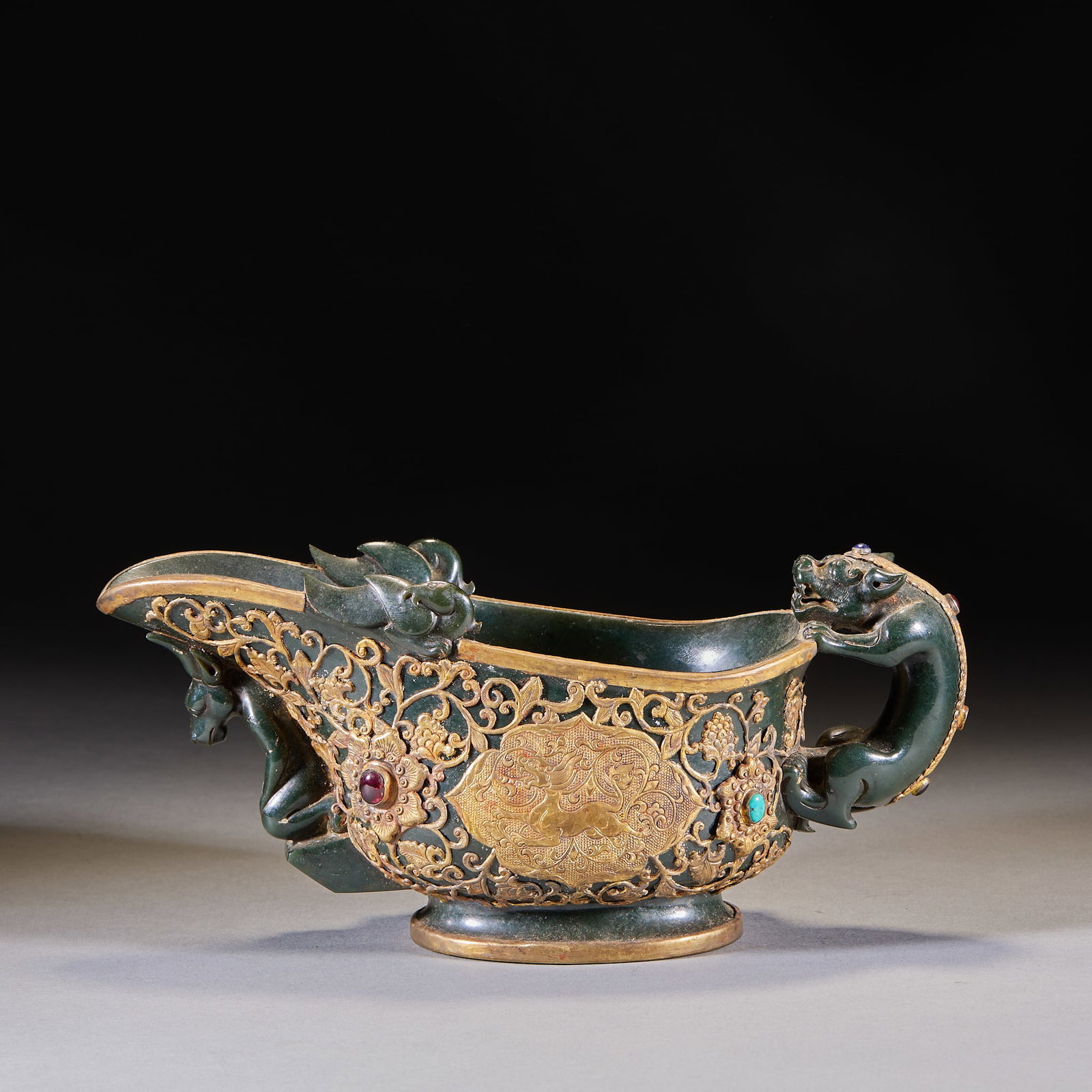 Qing Spinach-Jade Gold-Wrapped Gem-Inlaid Chi-Dragon Gong: A Qing spinach-jade gong, green in tone, the body carved with chi-dragons and partly gold-wrapped and gem-inlaid. Intricate and noble ?? a Qing jade display piece. H 12 cm, L 26 cm, W 10 cm.