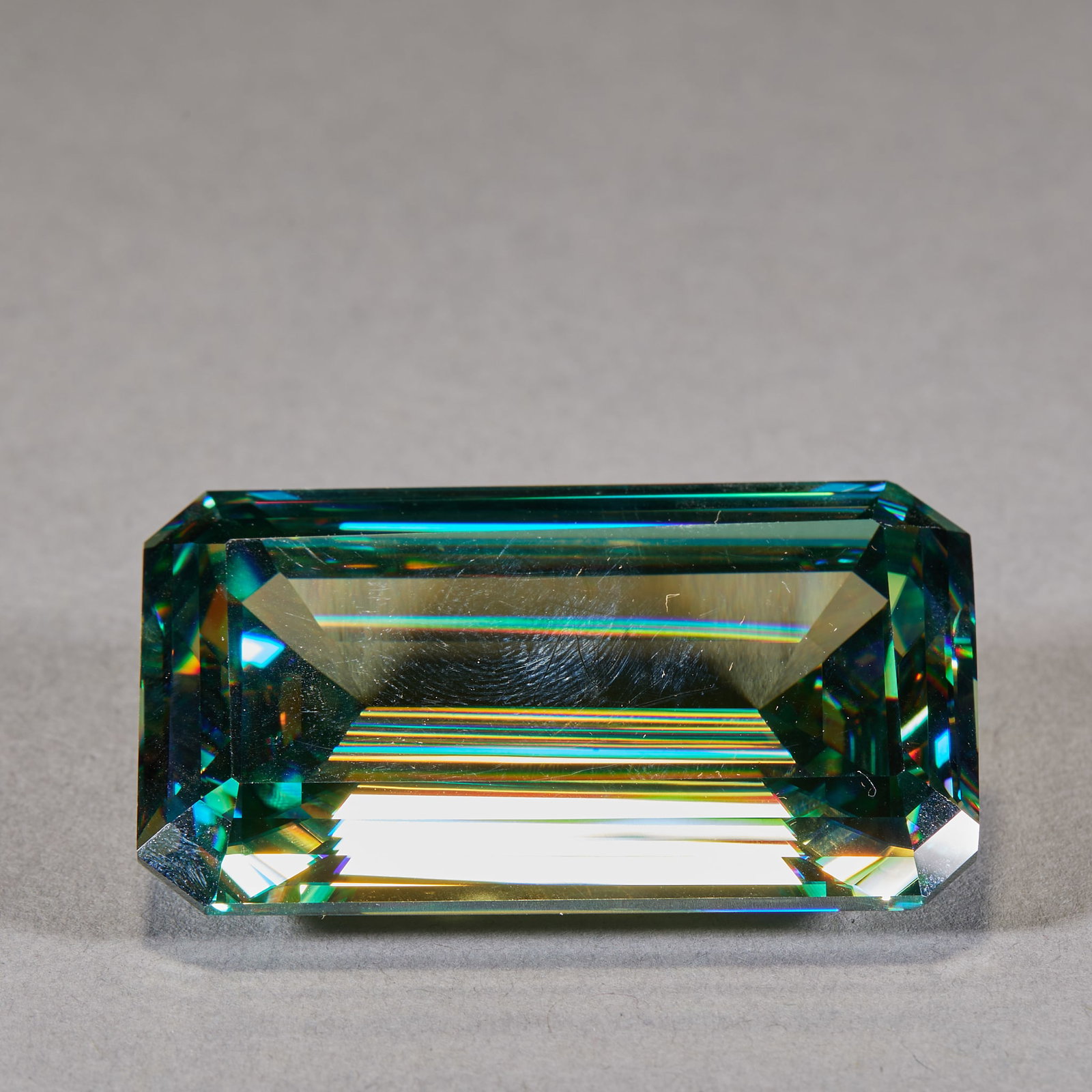 Rectangular Faceted Gemstone: A gemstone cut as a rectangular faceted stone, regular cutting, flashing brilliance, crystal colour. For setting or handling ?? of collecting value. H 1.5 cm, L 5 cm, W 3 cm, 44 g.