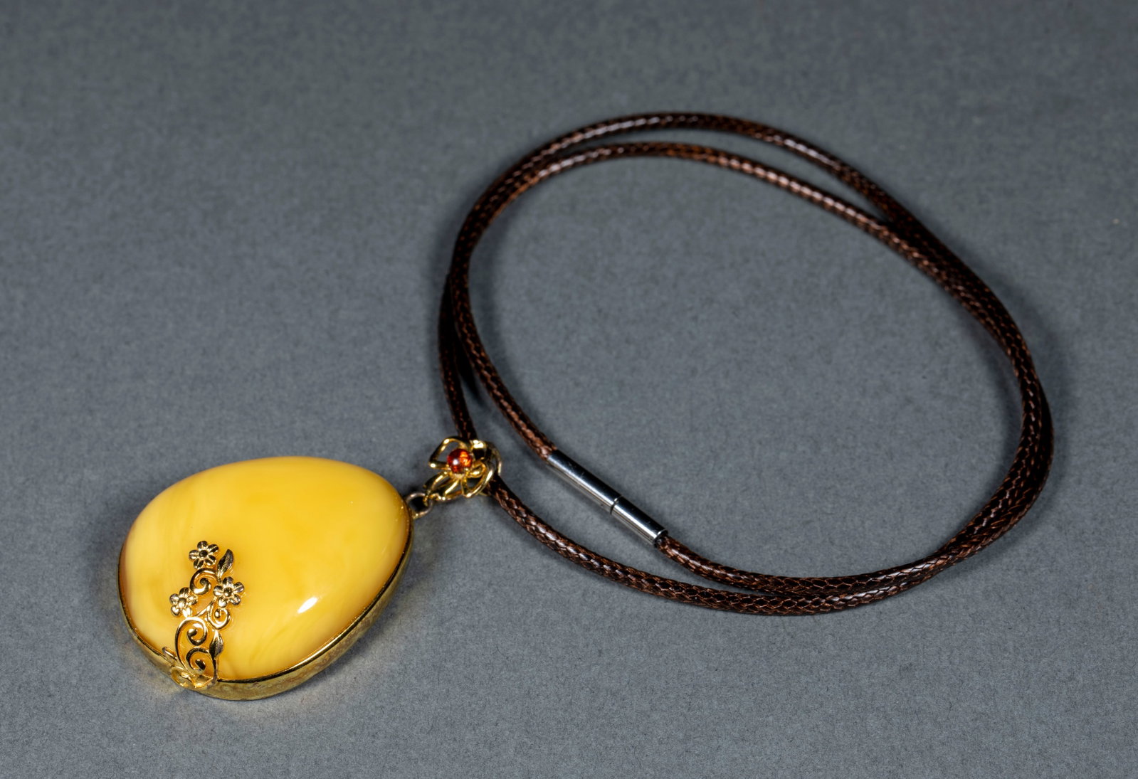Inlaid Amber Neck Ornament: An inlaid amber neck ornament of amber as the main, combined with gems and metal into a necklace form. The amber is warm and the setting sumptuous ?? worn at the neck, auspicious. T 1.3 cm, L 4.1 cm, 