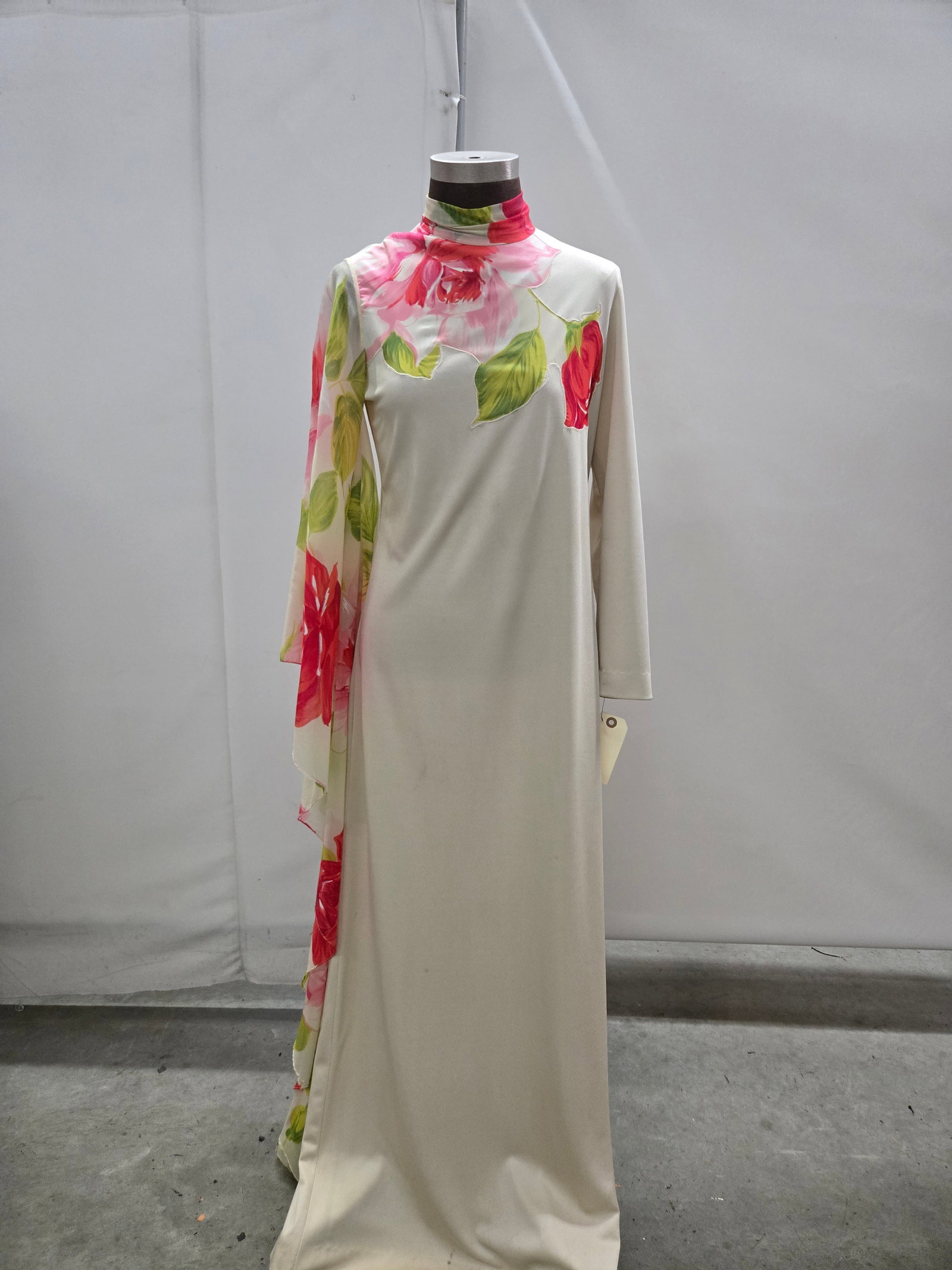 Evening gown, 1970s, beige poly crepe with red/pink/green floral chiffon, one Gothic sleeve/one stra: Evening gown, 1970s, beige poly crepe with red/pink/green floral chiffon, one Gothic sleeve/one straight sleeve, by Lilly Diamond. IMPORTANT NOTE TO BIDDERS: We are not an auction gallery but a liquid