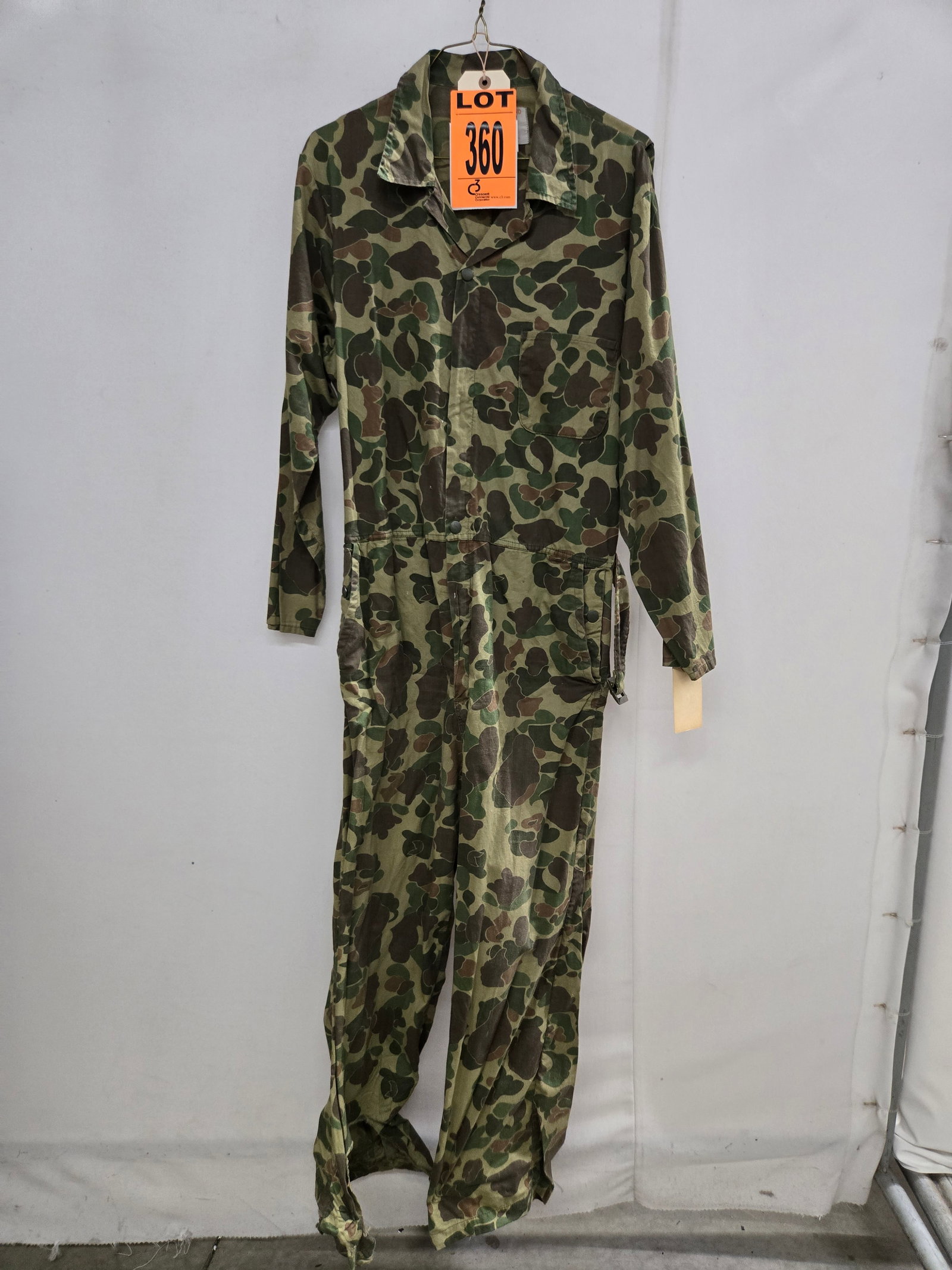 Black sheep brand duck hunter camo one piece coverall with waist belt. As worn by US advisors in: Black sheep brand duck hunter camo one piece coverall with waist belt. As worn by US advisors in Vietnam early 1960s in beautiful condition. Size 40 medium. (1 pcs). dated 1962 Location: Row 29A, Item