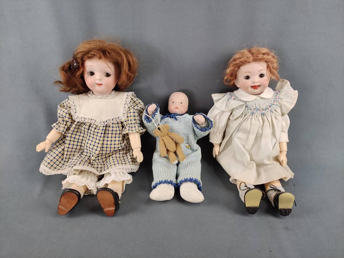 Three porcelain dolls, once Armand Marseille doll in plaid dress with white: Three porcelain dolls, once Armand Marseille doll in plaid dress with white collar and black shoes, brown wig with bow, also brown glass eyes and closed mouth, bisque porcelain head, remaining body is