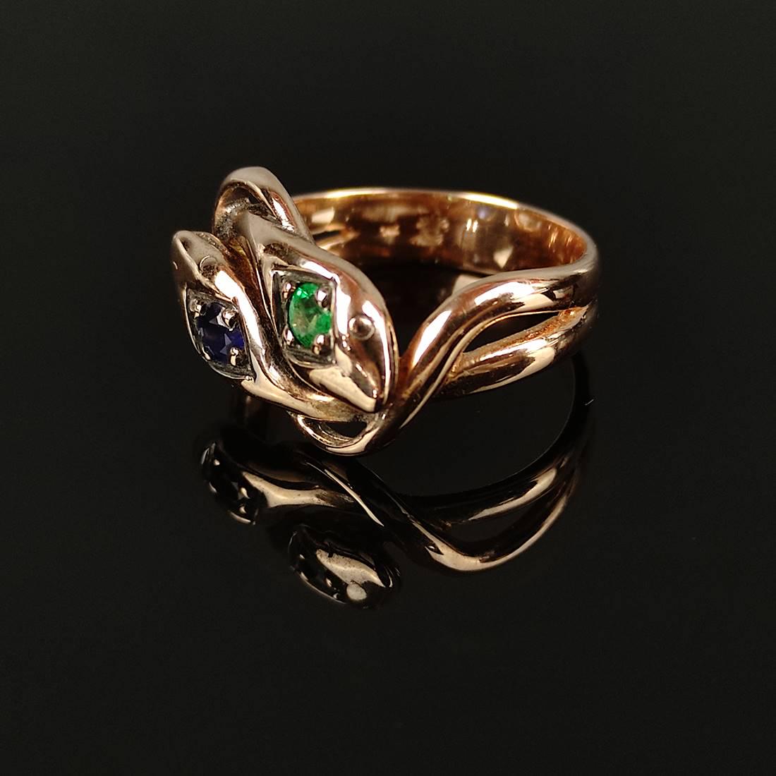 Fancy snake ring, 585/14K rose gold (hallmarked), total weight 6.35g, two i: Fancy snake ring, 585/14K rose gold (hallmarked), total weight 6.35g, two intertwined snakes, on one snake head an emerald on the other a sapphire, each a diameter of approx. 3.12mm, ring size 54. Aus