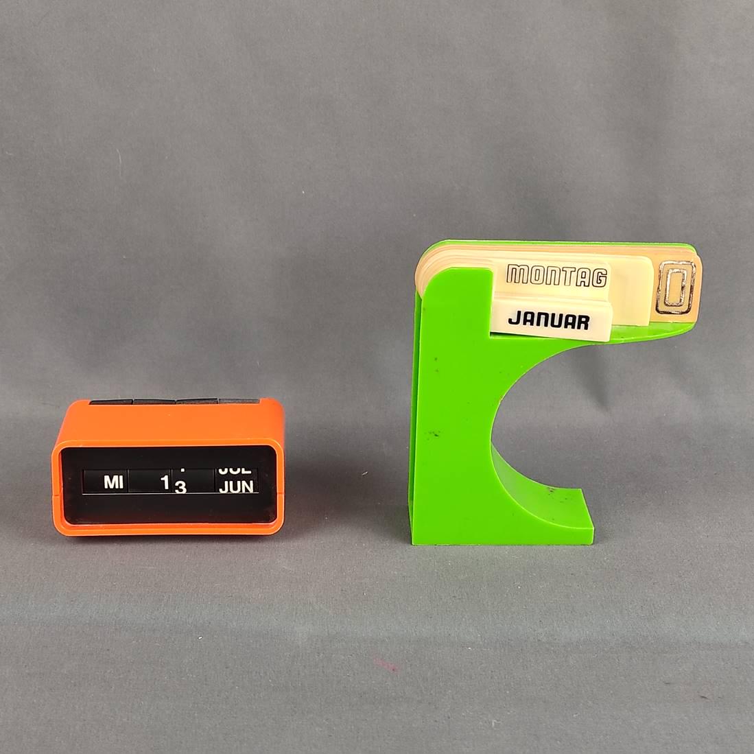 Two desk calendars, "arlac dati" by DBGM Design Halm, 60s/70s, perpetual ca: Two desk calendars, "arlac dati" by DBGM Design Halm, 60s/70s, perpetual calendar, orange plastic case, approx. 10x5cm, another desk calendar made of green plastic, signs yellowed as well as slight da