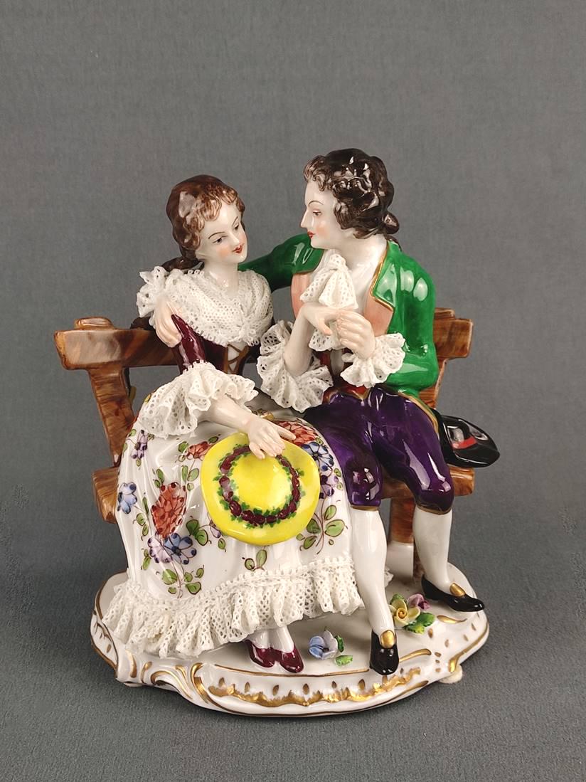 Porcelain figure "sitting couple", Aelteste Vorstedter Porzellanmanufaktur, 20th century, baroque: Porcelain figure "sitting couple", Aelteste Vorstedter Porzellanmanufaktur, 20th century, baroque couple sitting on a bench, the lady's dress is decorated with tulle porcelain, polychrome painted, roc