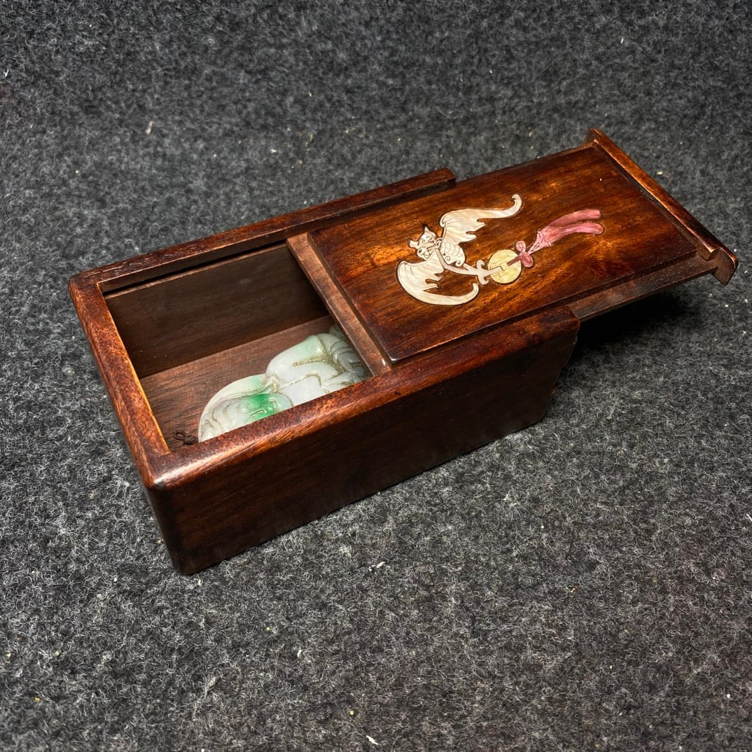 A rosewood and mother-of-pearl inlaid mechanical case contains a jade pendant. (1 of 9)
