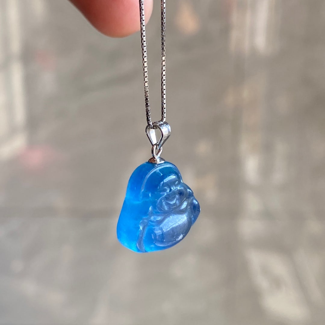 Natural aquamarine carved Buddha pendant: This natural aquamarine carved Buddha pendant is a beautiful deep blue, depicting a full and compassionate Buddha image. It has a lustrous and translucent appearance. Dimensions: 16 x 17 x 7 mm, Weigh
