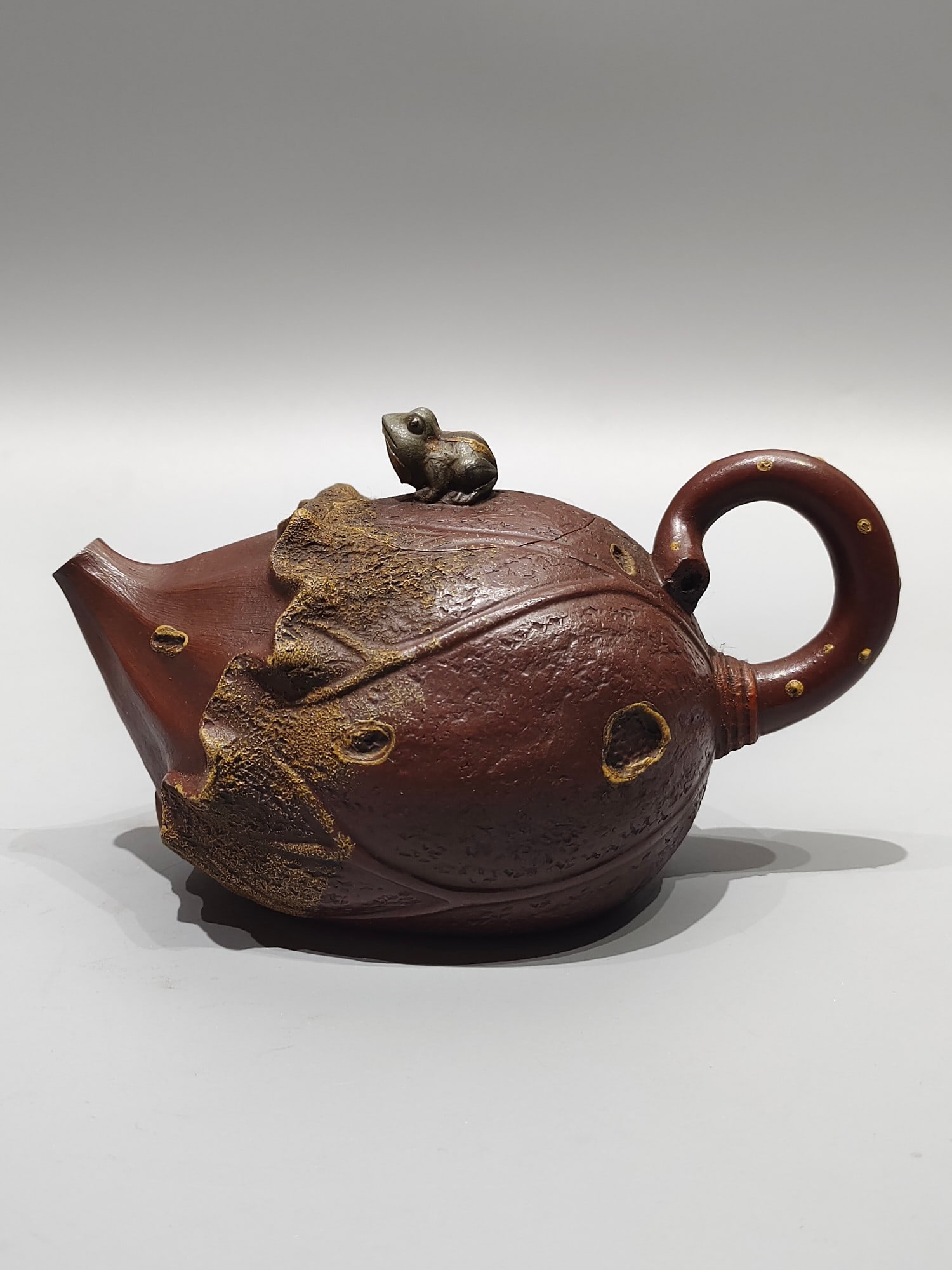 A treasured old teapot with a frog and lotus leaf design. (1 of 7)
