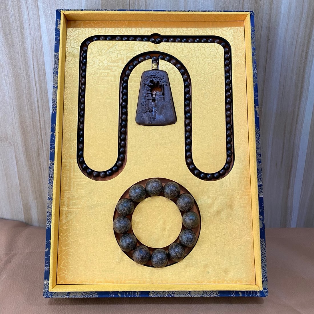 Agarwood bracelets and agarwood prayer bead necklaces are displayed in a brocade box. (1 of 9)