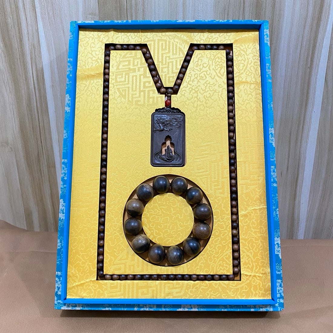 Agarwood bracelets and agarwood prayer bead necklaces are displayed in a brocade box. (1 of 11)