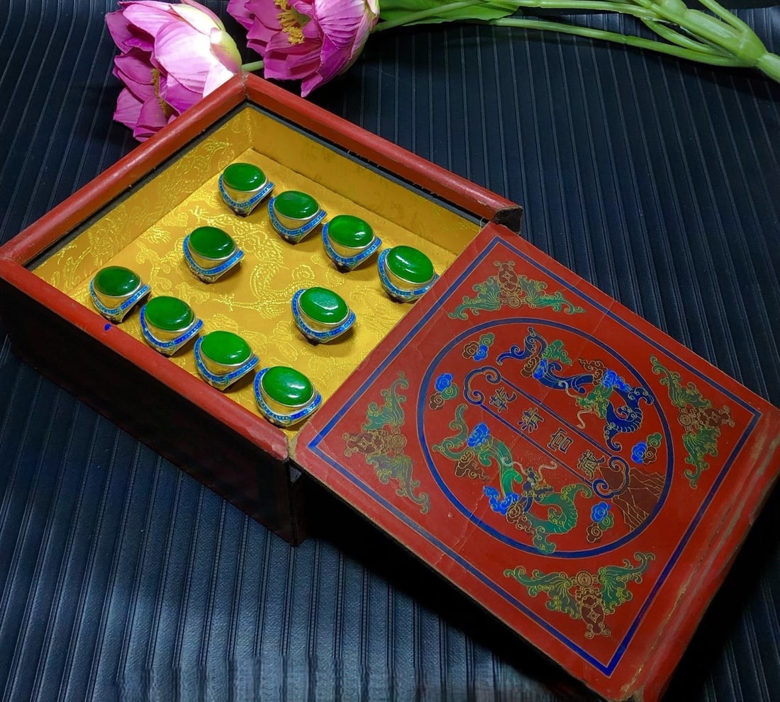 A lacquerware painted wooden box contains a silver ring inlaid with imperial green jade.: A lacquerware painted wooden box contains a silver-inlaid imperial green jadeite ring. The box is made of superior materials, with an icy, translucent, and lustrous green color, beautiful luster, and