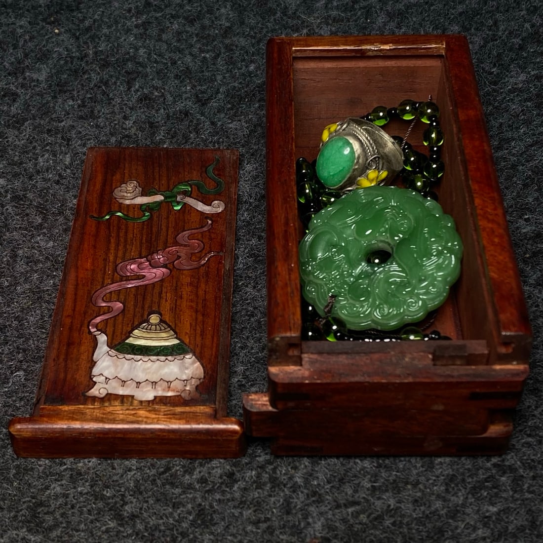 A rosewood jewelry box inlaid with jade contains a jade necklace paired with a cloisonne jade ring. (1 of 9)