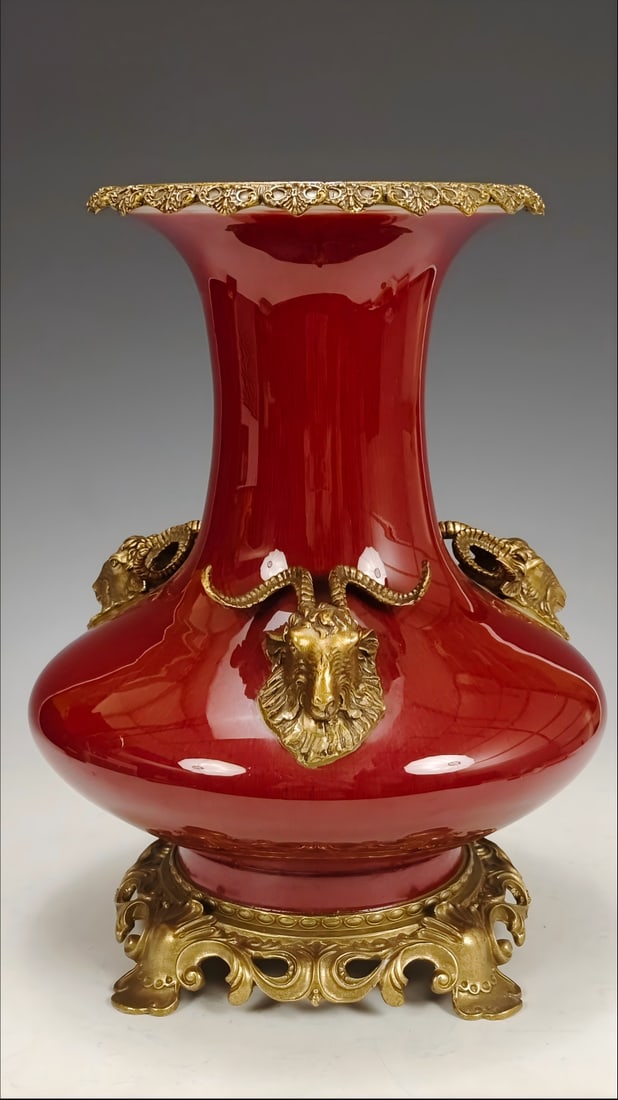 A plain red-glazed vase with a single layer of glaze and bronze inlay of deer head design, made: Formerly in the collection, this is a plain red-glazed vase from the Qianlong period of the Qing Dynasty, depicting a vase with a bronze inlay of a deer's head motif. The vase in the picture is