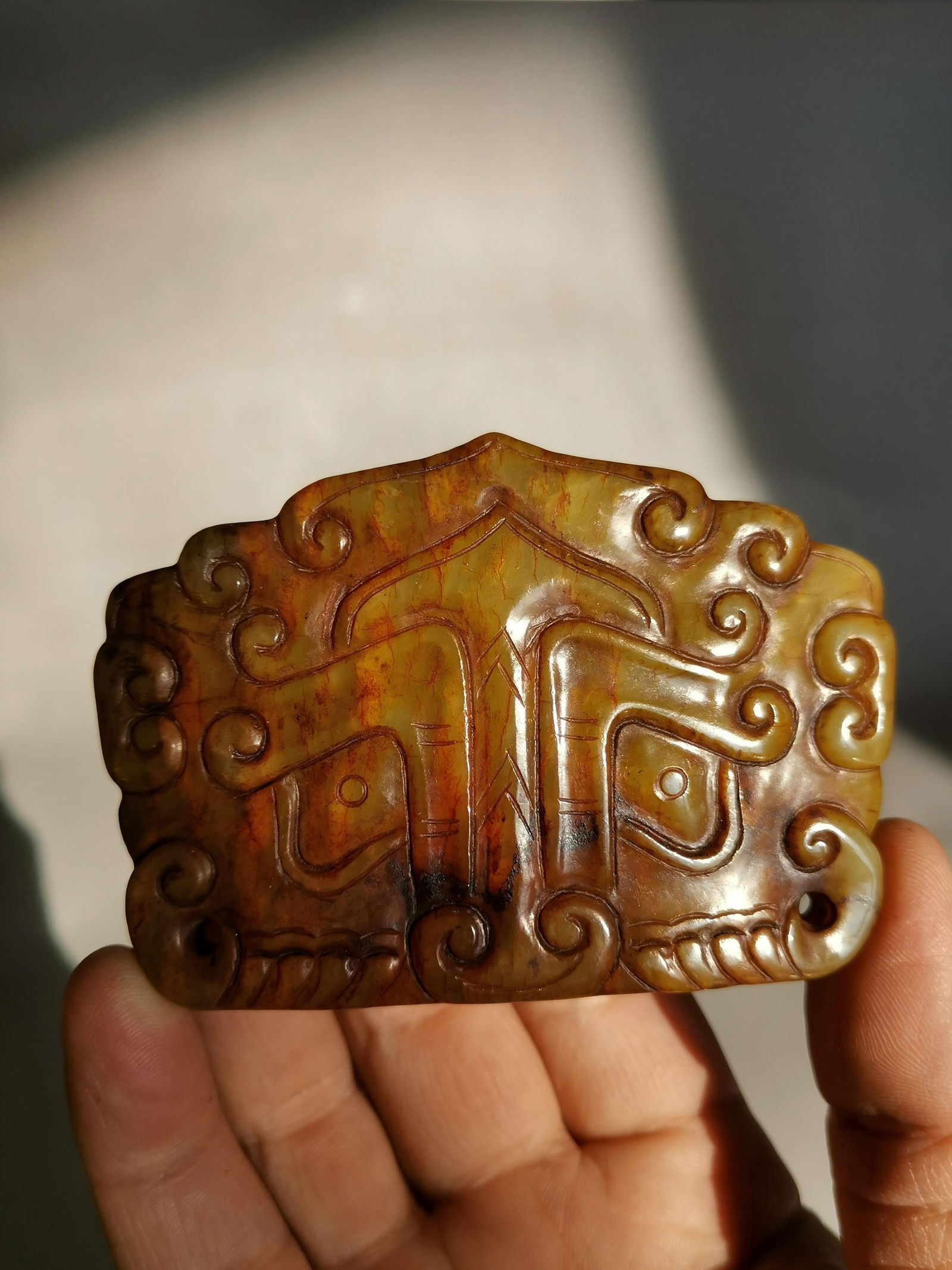 Ancient Jade Belt Buckle with Animal Mask Pattern: This ancient jade belt buckle with animal mask design is made of Hetian yellow jade, with a warm and smooth texture and a surface covered with natural reddish-brown patina. The face of the buckle is c