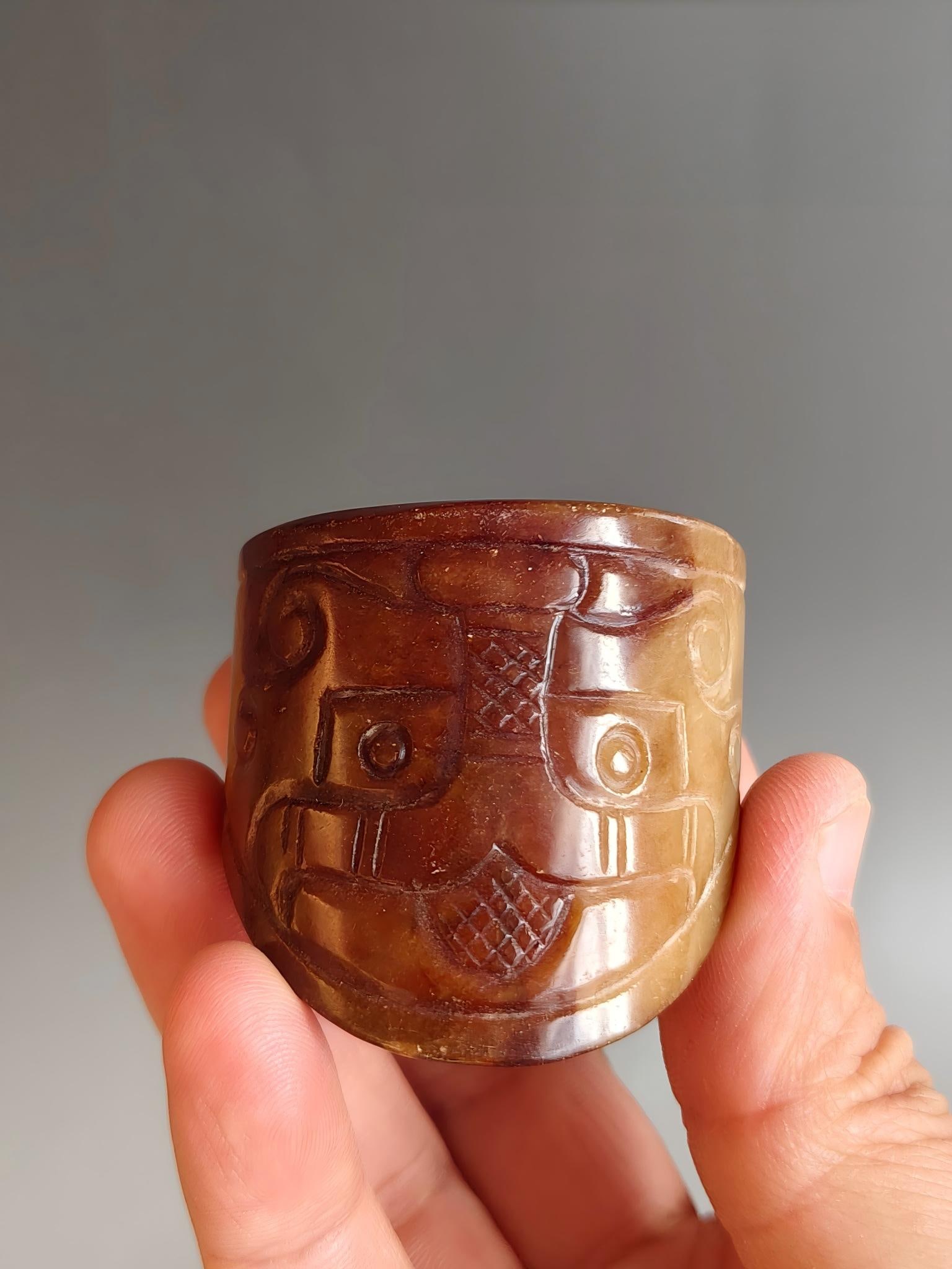 Ancient jade animal mask patterned tubular artifact: This ancient jade animal-face patterned tubular artifact is a condensation of the divine right and ritual system of the Shang and Zhou dynasties. It is 4.6cm in diameter, 4.4cm in length, and weighs 5