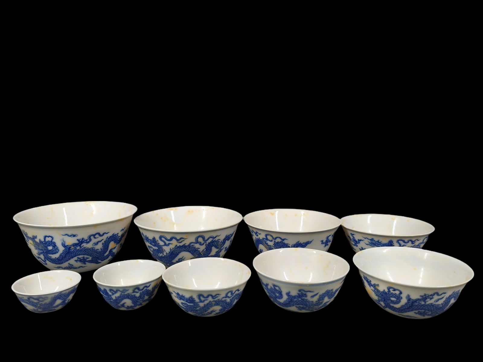 Thin-walled blood porcelain blue and white double dragon pattern nested bowls made during the: A set of three thin-walled, blood-red porcelain blue-and-white bowls with double dragon design, made during the Chenghua period of the Ming Dynasty. The largest bowl measures 11.7 x 5.5 cm, and the sm