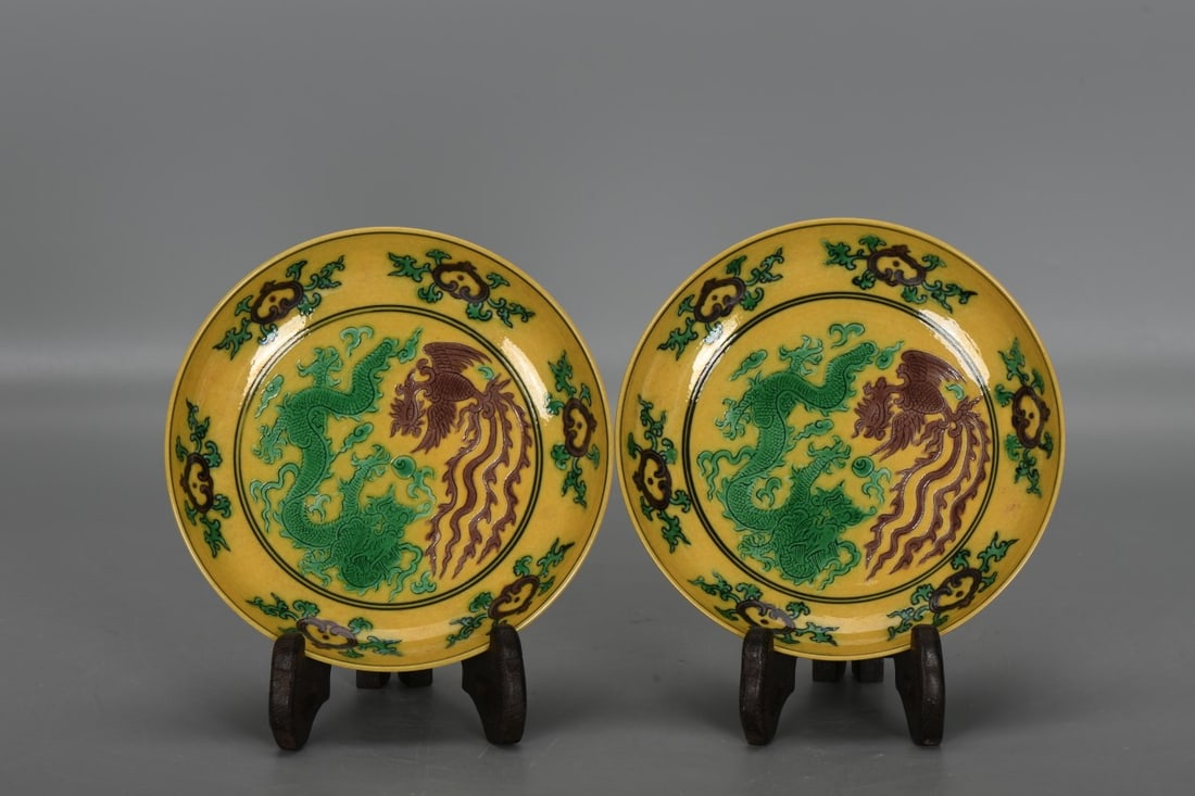 A pair of Qing Dynasty, Guangxu period sancai (three-color glazed) dragon and phoenix patterned: A pair of Qing Dynasty, Guangxu period sancai (three-color glazed) dragon and phoenix patterned plates, 3 cm high, 13.5 cm in diameter at the mouth, and 8 cm in diameter at the base. Provenance:Privat