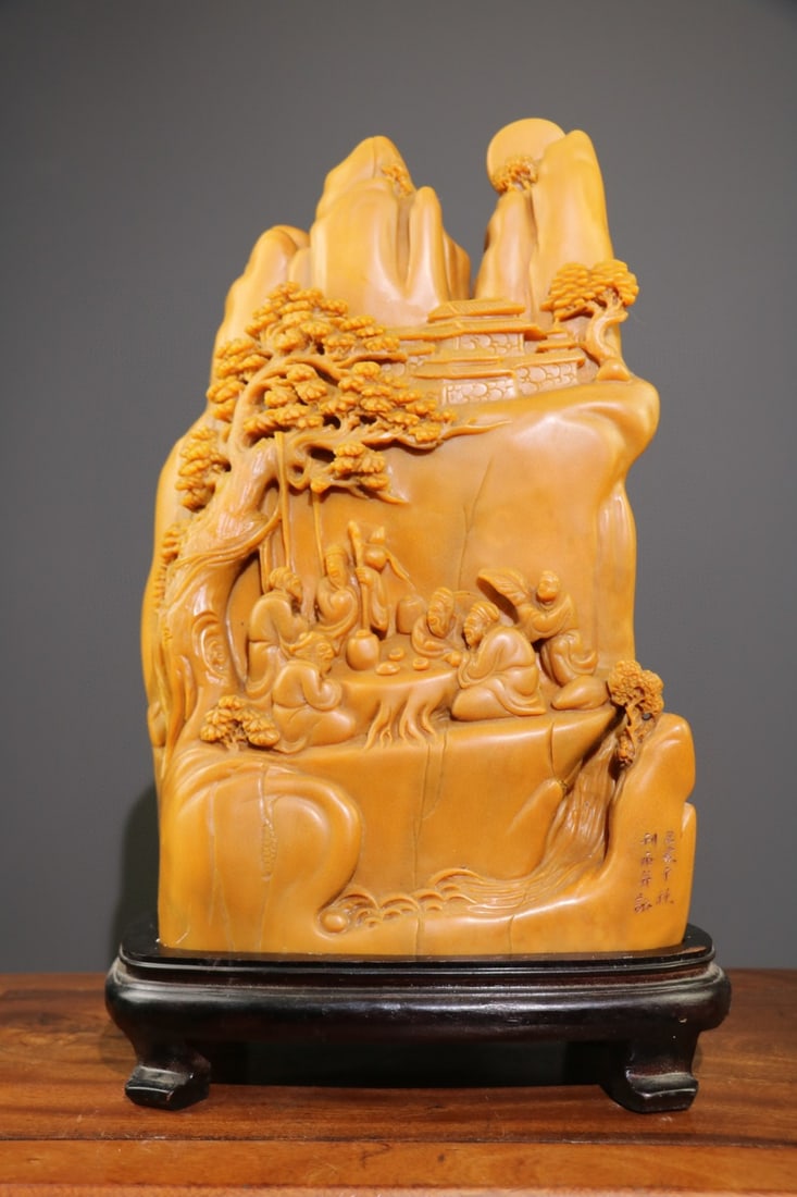 A large, exquisitely crafted Tianhuang stone ornament, "Leisurely Gathering Under the Pine Trees,": A large, exquisitely crafted Tianhuang stone ornament, "Leisurely Gathering Under the Pine Trees," is hand-carved with a landscape scene and figures depicting an elegant gathering. It is large in size