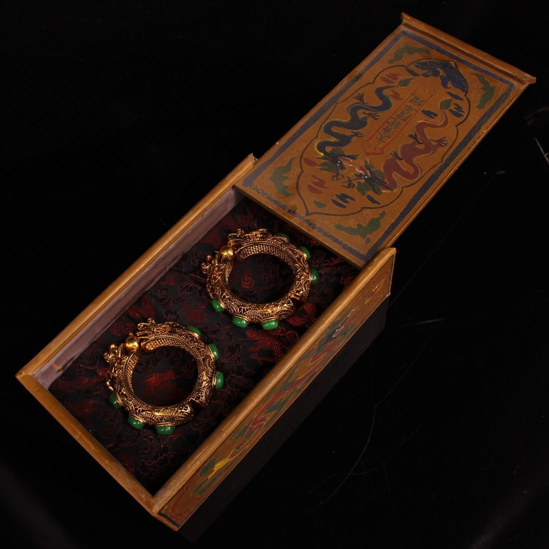 A pair of Qing Dynasty imperial gilt-gold dragon-head bracelets inlaid with gemstones.: A pair of exquisitely crafted, gem-encrusted dragon-head bangles, made for the Qing Dynasty imperial court, are in excellent condition and uniquely designed. The total weight is 1034g. The box measure