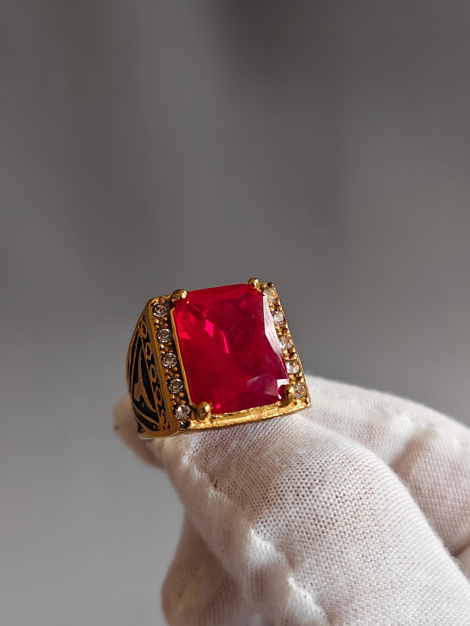 18K gold ring set with rubies:  The rectangular center stone is a vibrant red, surrounded by smaller diamonds and black gold embellishments, giving it a vintage feel. The ring measures 2.0cm and weighs 17.8g. The 18K