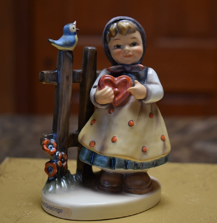 Hummel "Sweet Greetings" Figurine: Measuring 4 1/4" high, 2 7/8" at base, titled "Sweet Greetings", depicts a girl holding a heart and a bird signing on the fence. No issues, good condition, Domestic Shipping is $12.